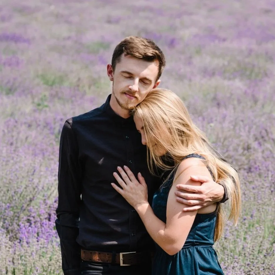 Woman kneeling at a gravesite holding a bouquet of white flowers in a cemetery.