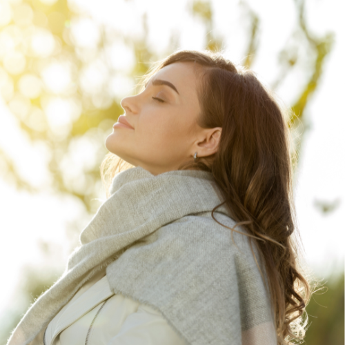 A woman with closed eyes relaxing at a desk, with a digital overlay of two people hugging in a cosmic scene.