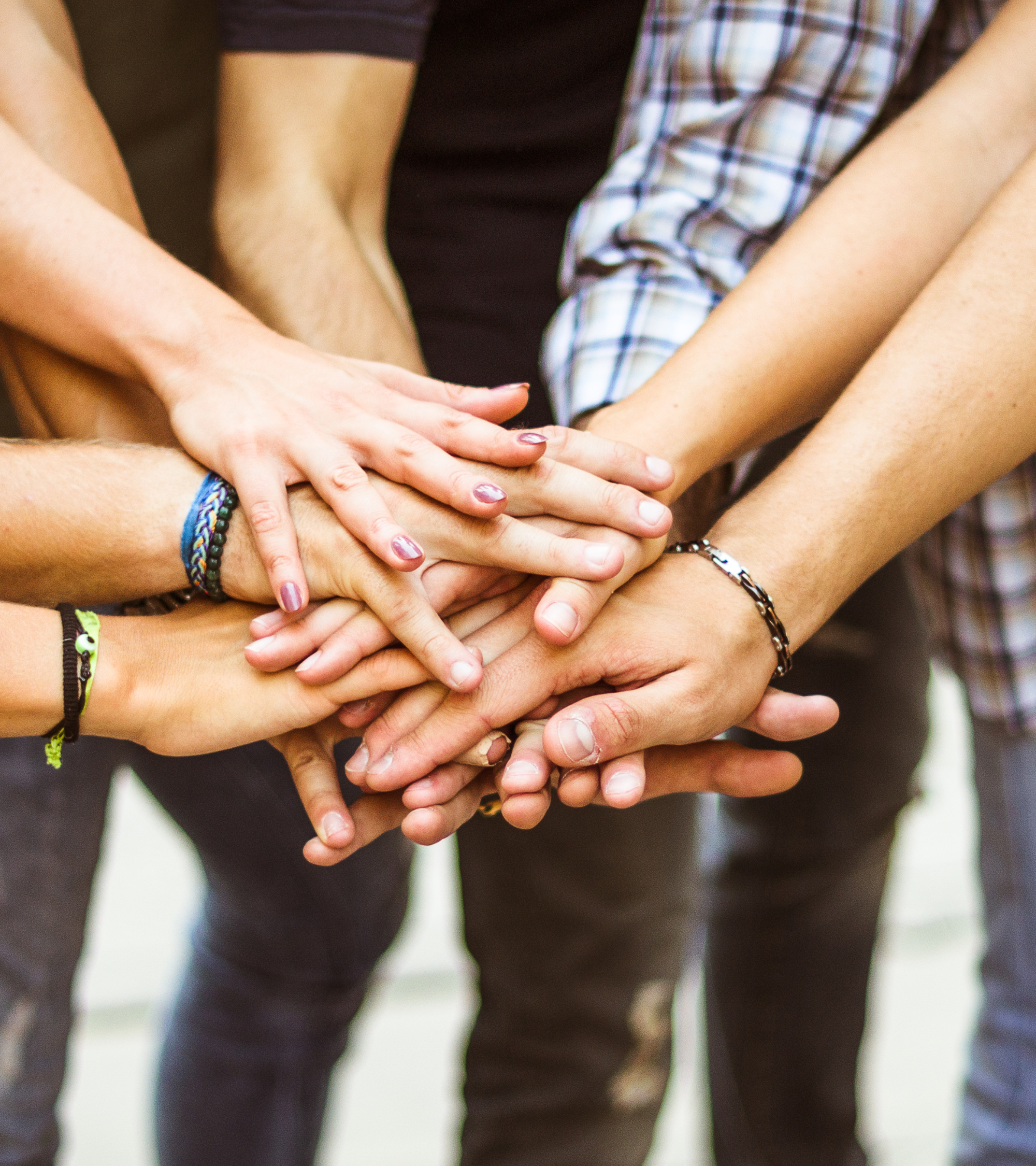 Multiple hands stacked together, symbolizing teamwork and unity.