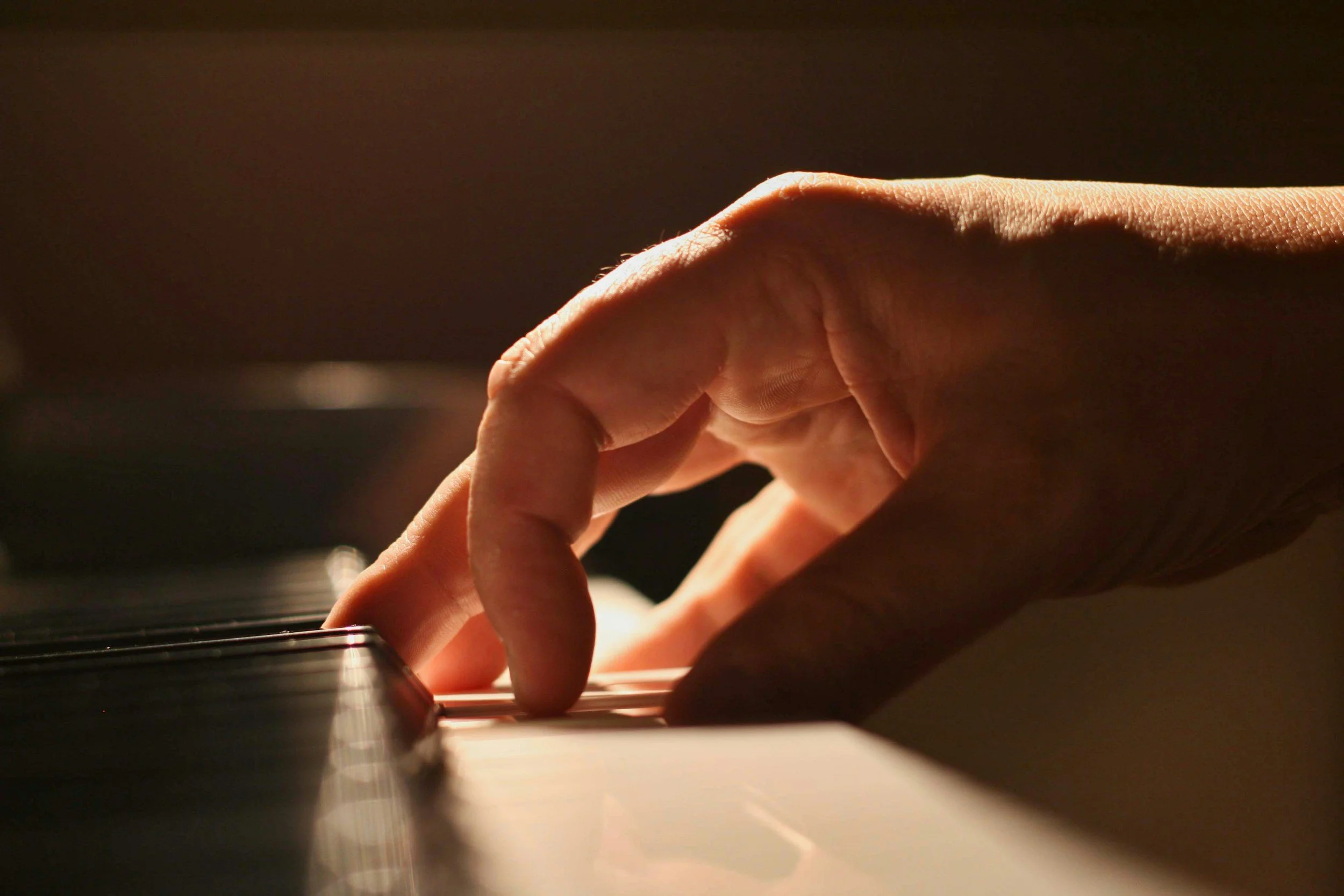 a close up hand of an adult piano student working on technique in an online lesson