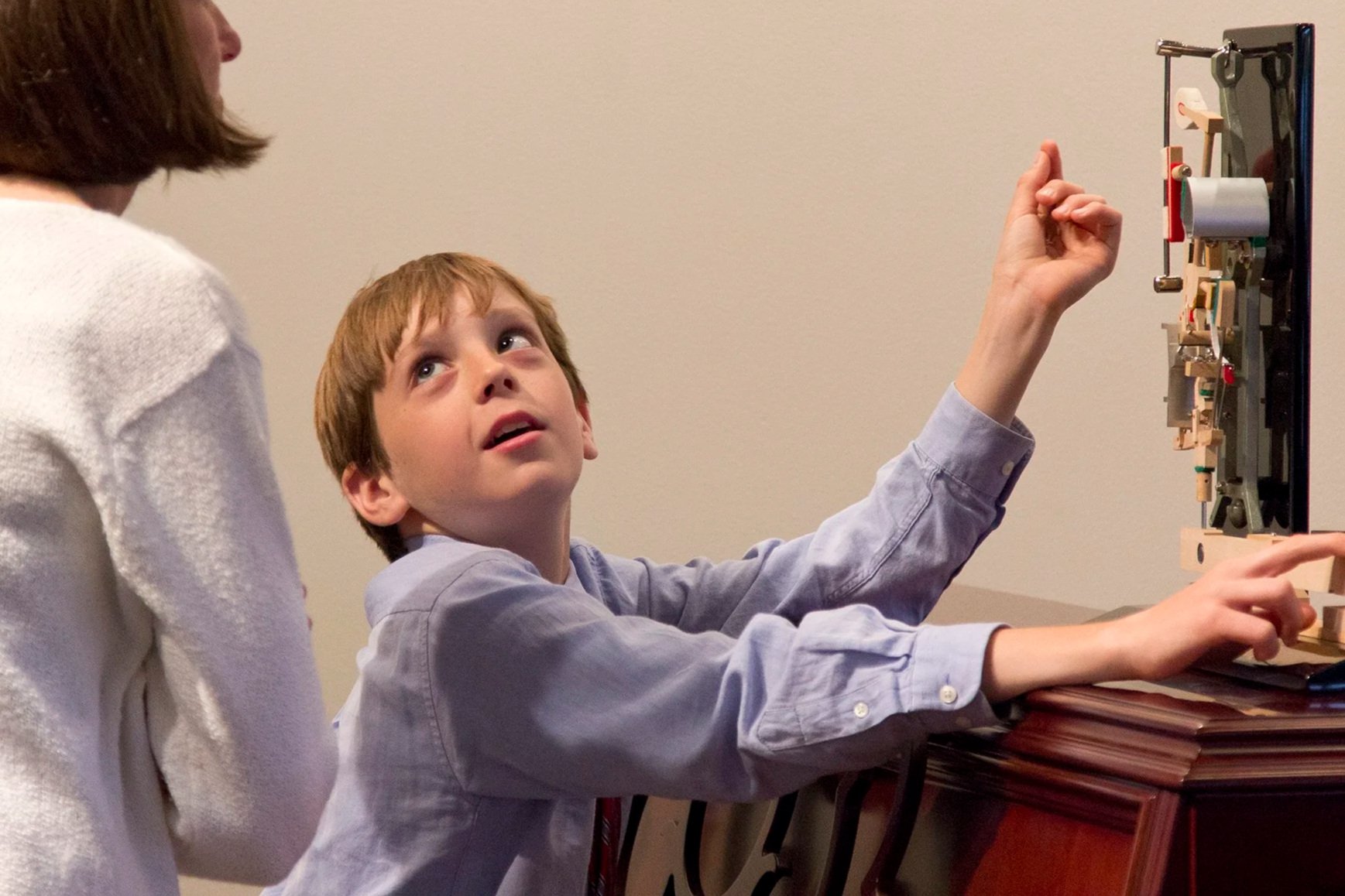 Piano student from Chapel Hill North Carolina looking at the machanics of the piano hammer above a piano at a recital in Raleigh North Carolina