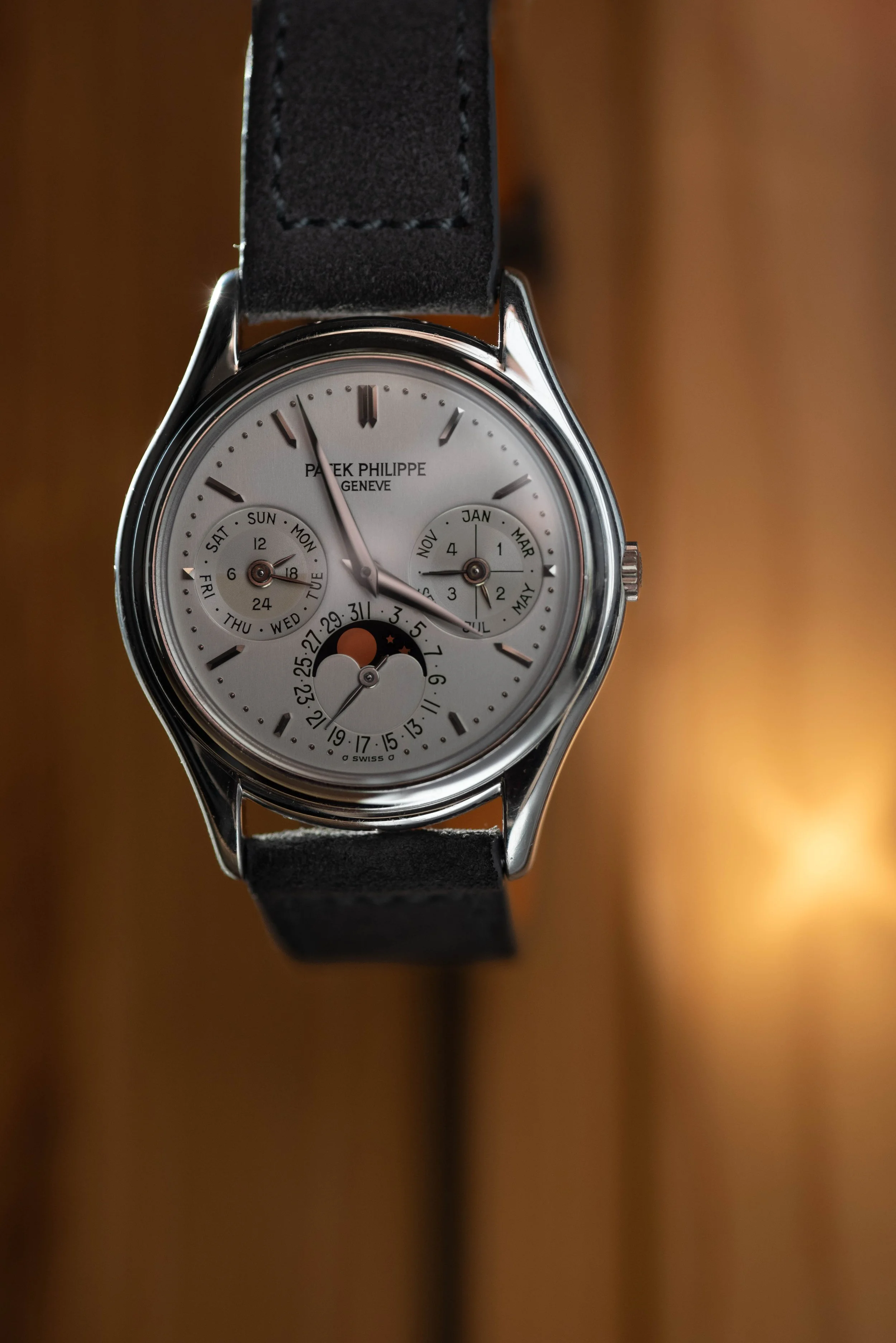 Patek Philippe 3940p floating in front of an illuminated wood background