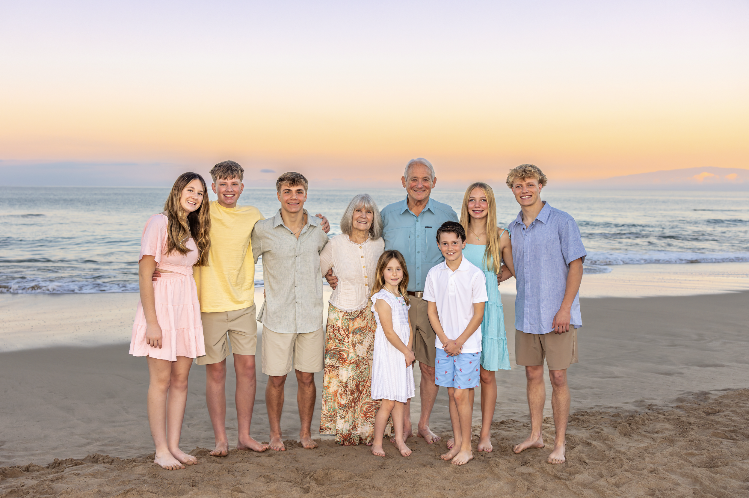 Family of ten standing on the beach at sunset taking photos in Hawaii with their photographer Cynthia Buckles with CynthiArtistry. Cynthia Buckles is rated best photographer on the Big Island of Hawaii with over 50 amazing reviews on Trip Advisor.