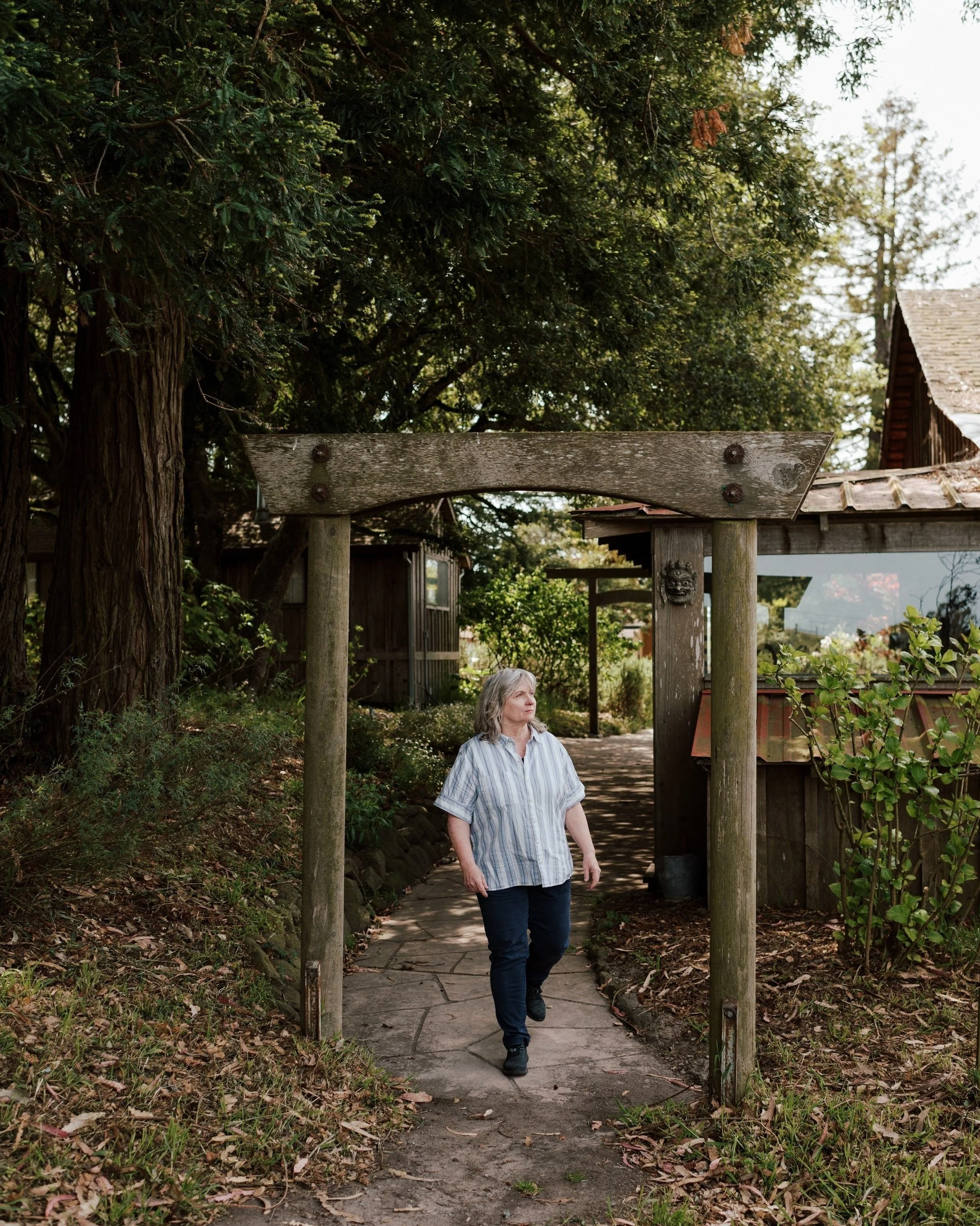 White woman walking under a wooden archway.