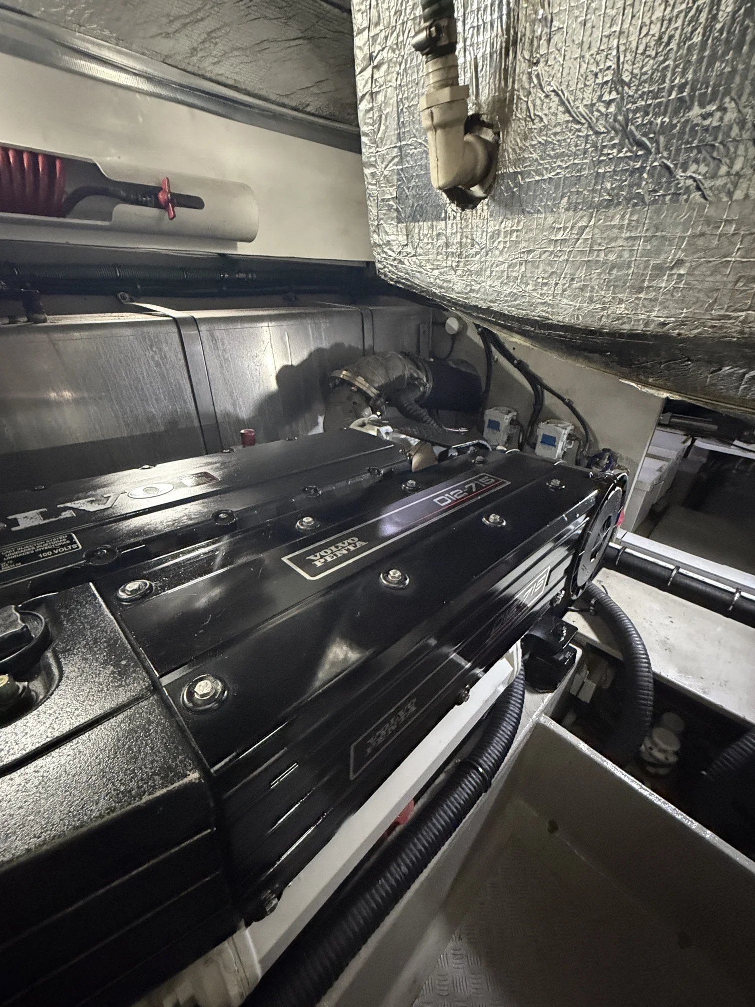 Close-up of an engine and mechanical parts inside a vehicle, with hoses, wires, and metal components visible.