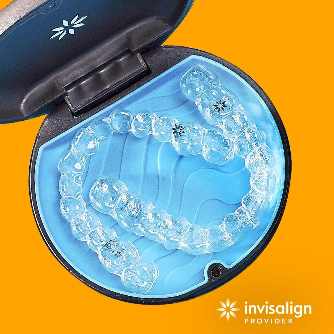 Clear dental aligners inside an Invisalign case with an orange background.