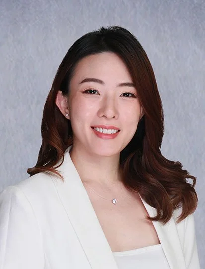 A young woman with long hair tied to one side, wearing a black medical uniform with the name tag 'Dr. Samantha Umao' and a smile.