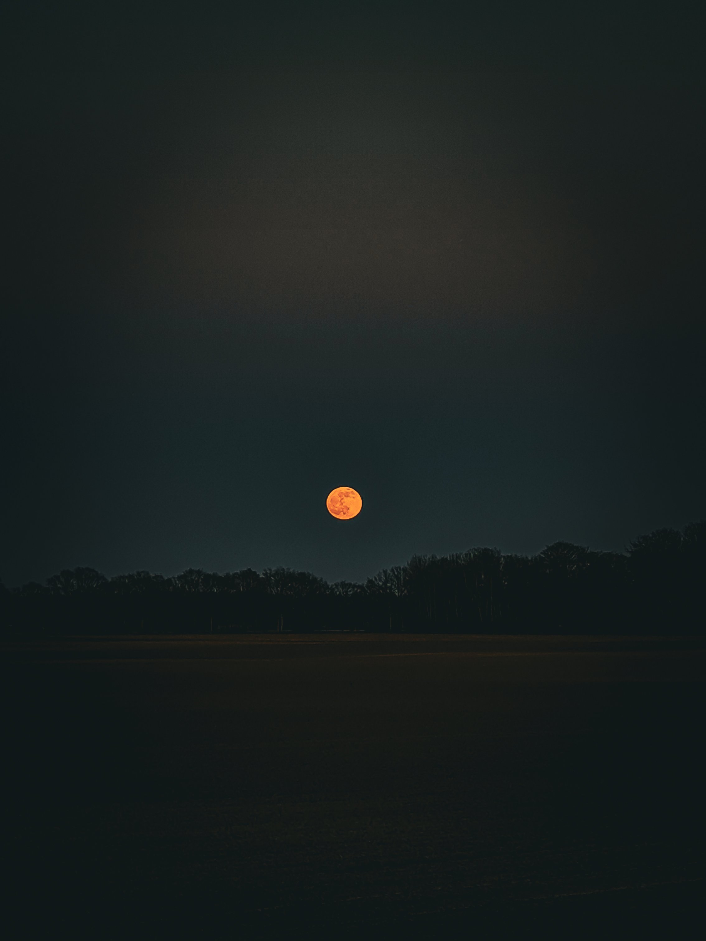 Ondergaande maan boven een Hollands landschap