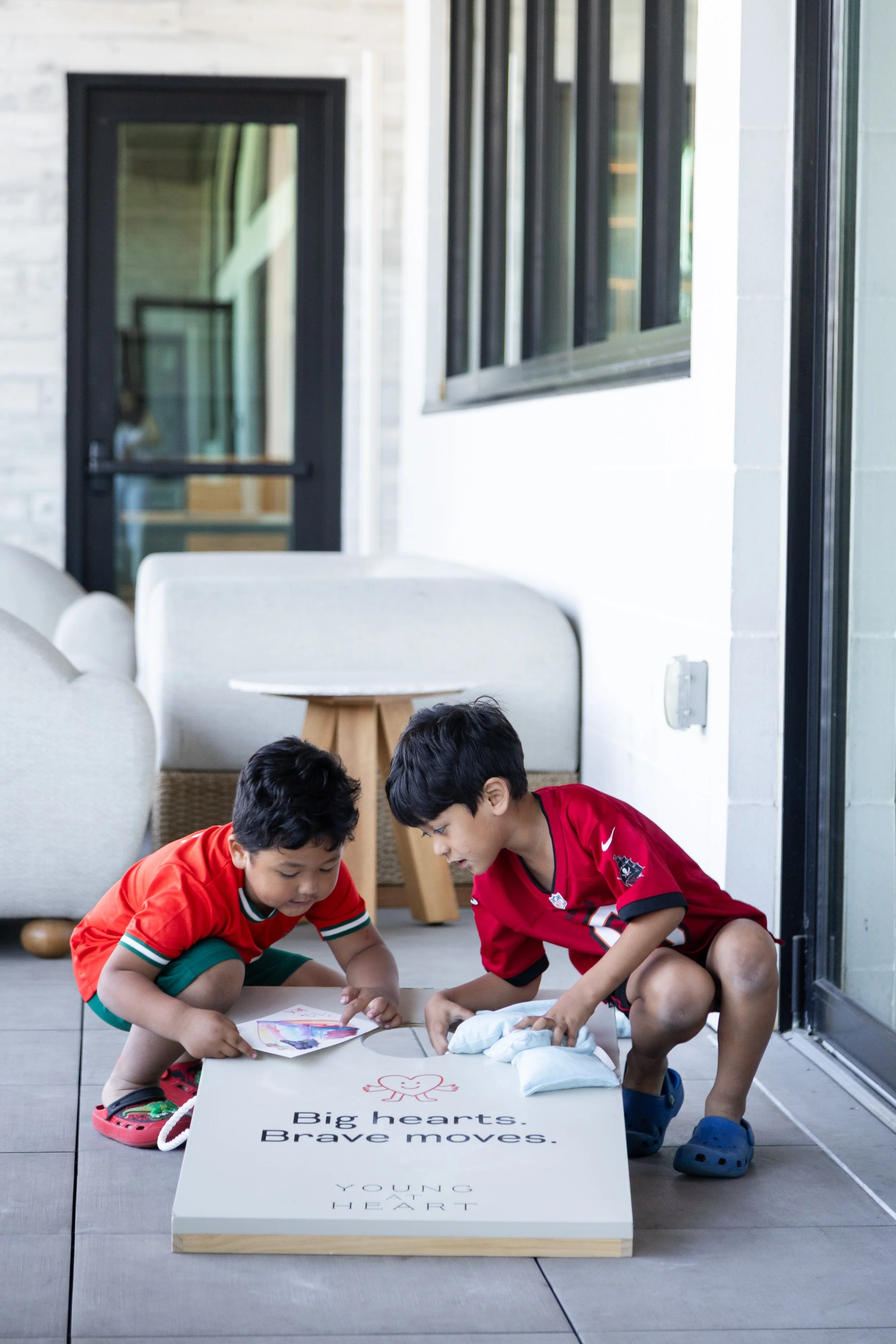 Kids playing cornhole outside at Young at Heart's playdate in Tampa