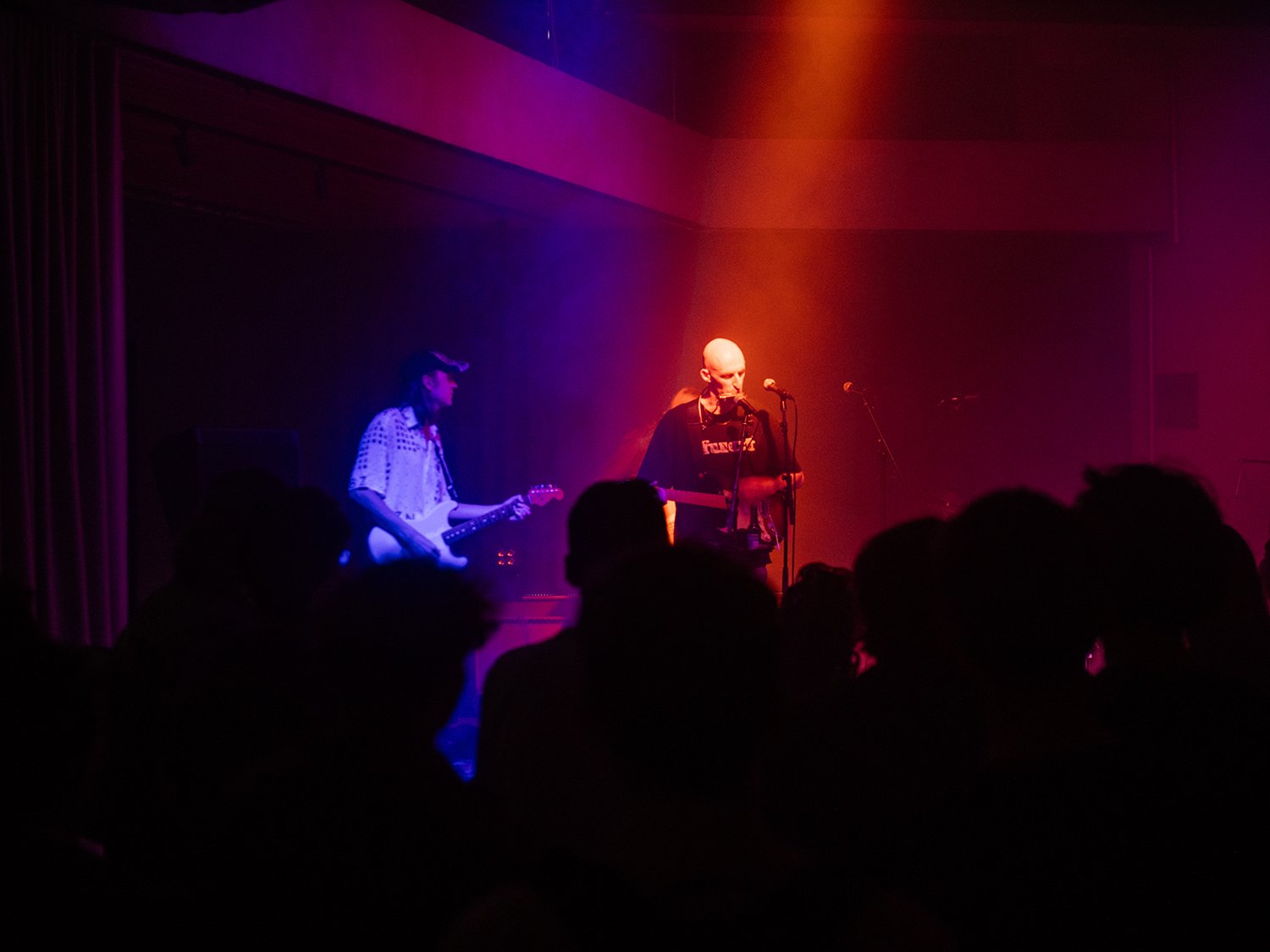 En mann som synger på en scene, sammen med et band og foran et publikum