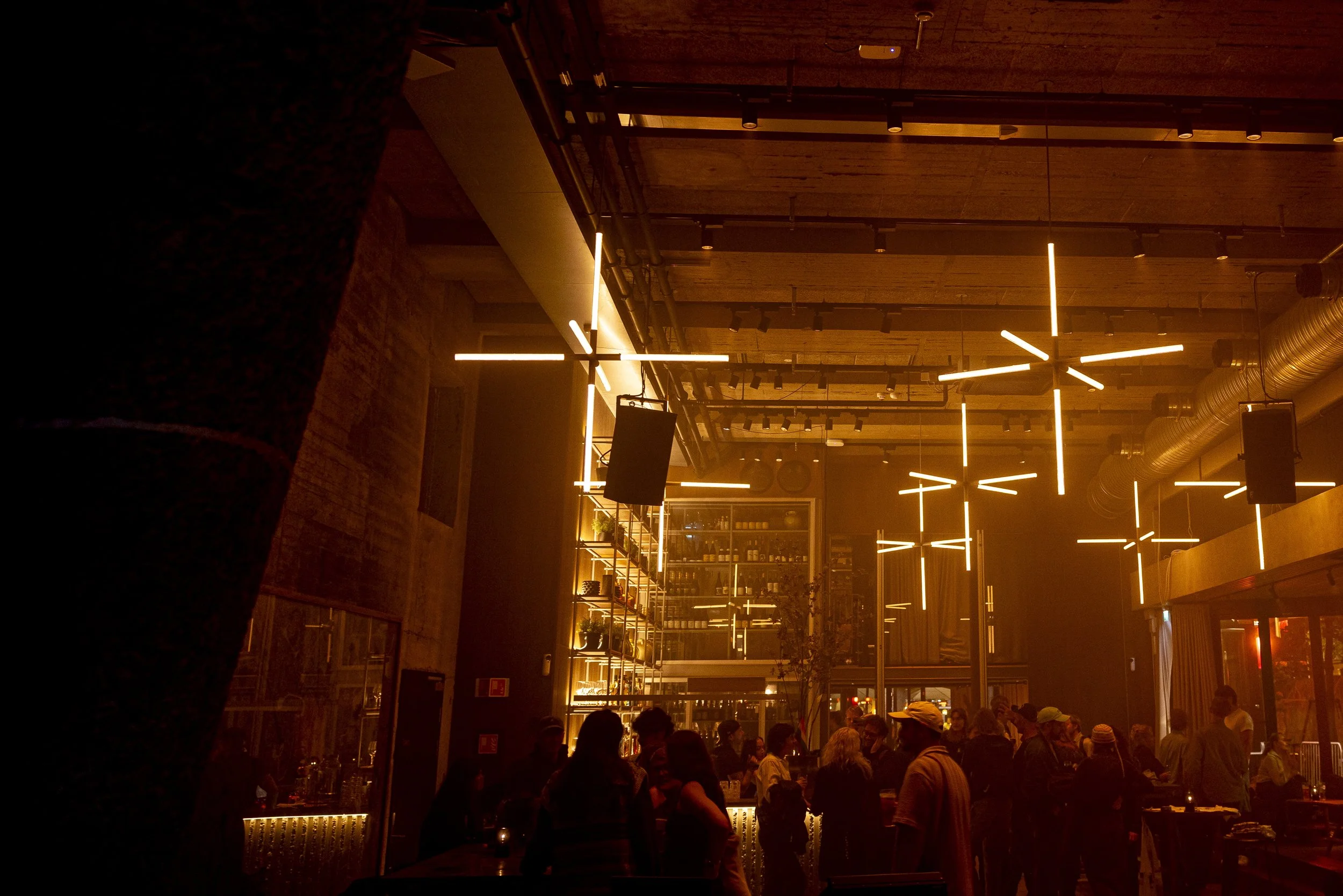 Kveldsstemning på Trekanten. Fullt barområde med varme lysinstallasjoner og livlig atmosfære.