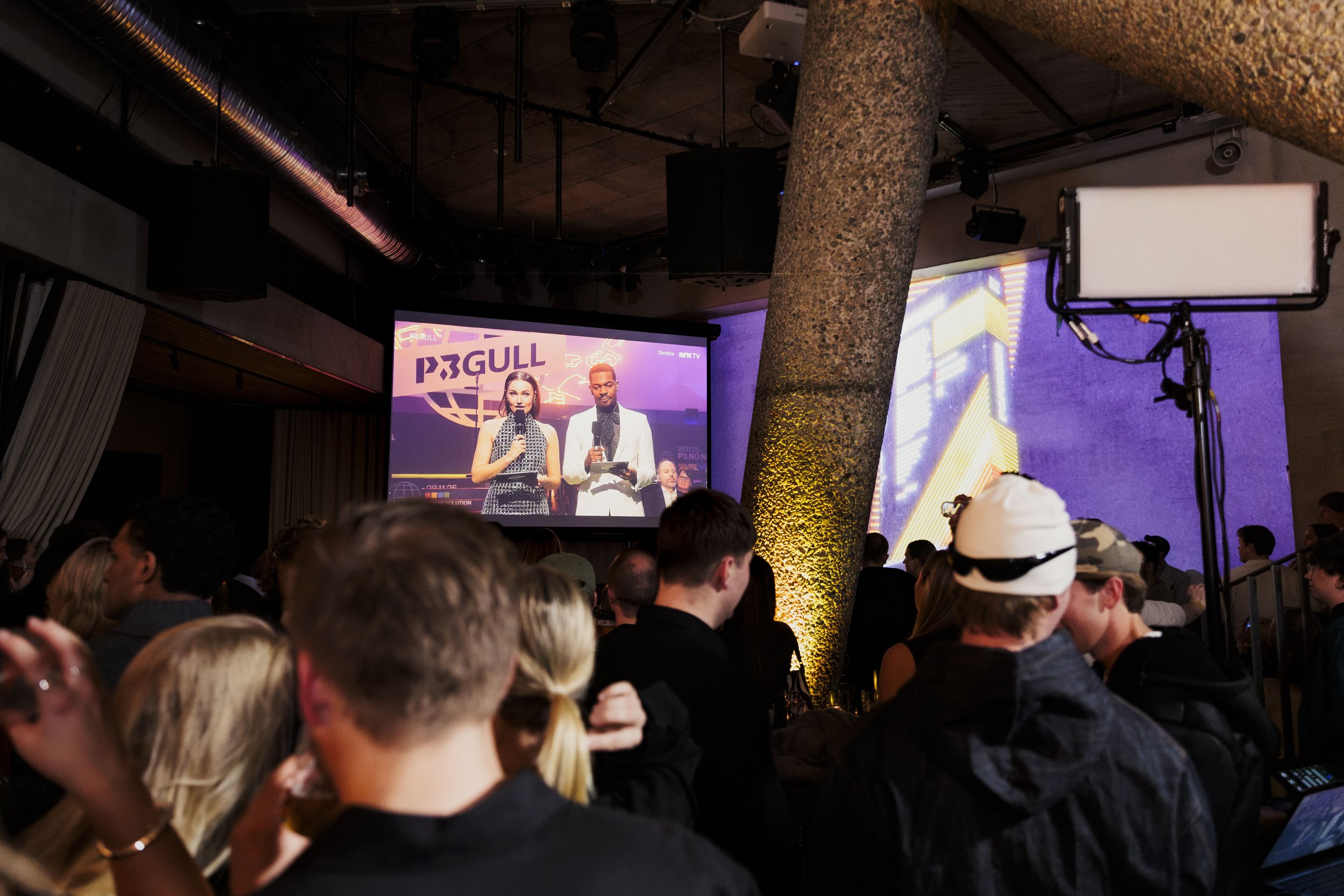 Publikum følger P3 Gull-sendingen på storskjerm hos Trekanten, med lysinstallasjoner og stemningsfullt miljø.