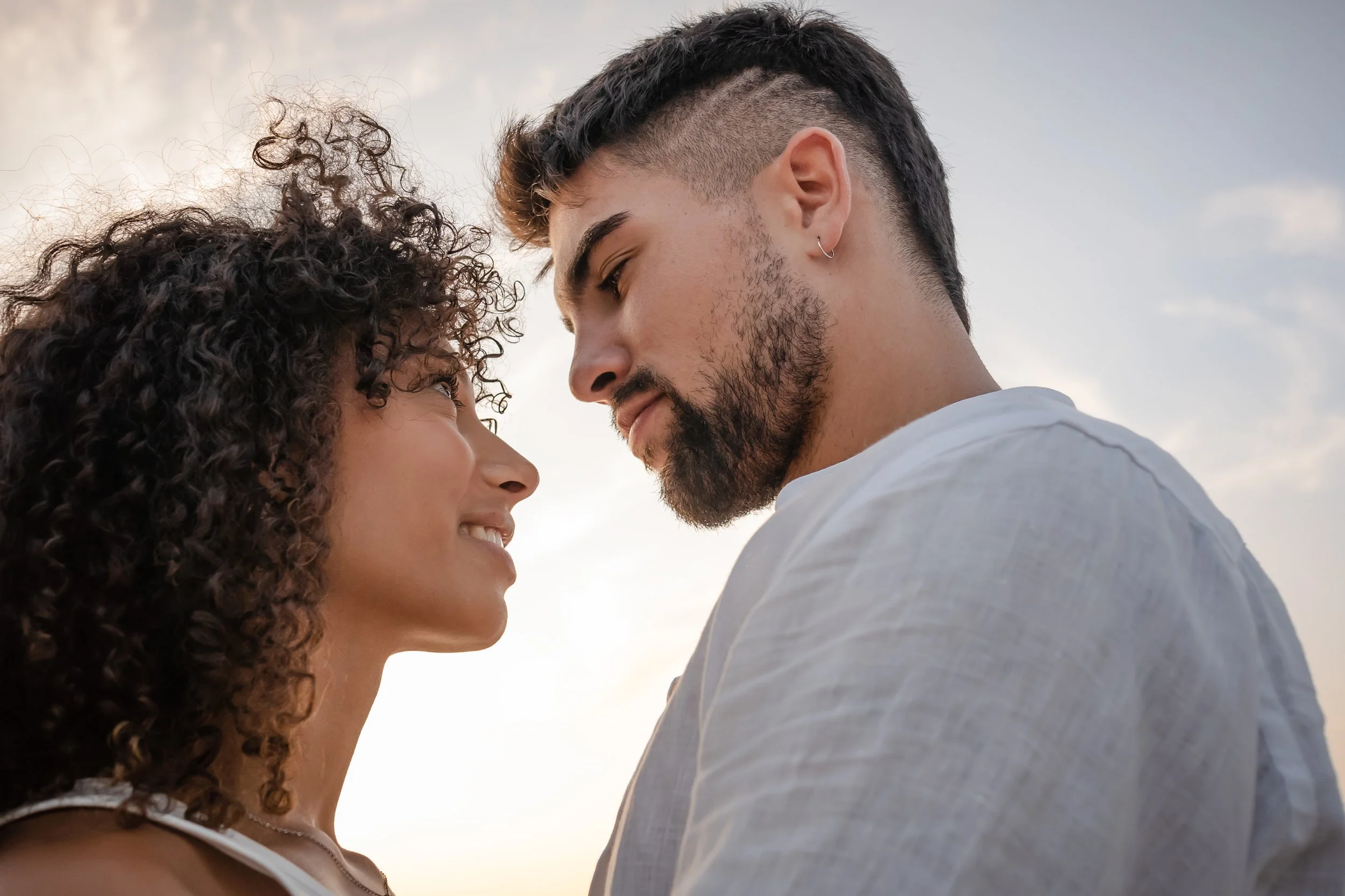 man and woman looking into each other's eyes against sky background