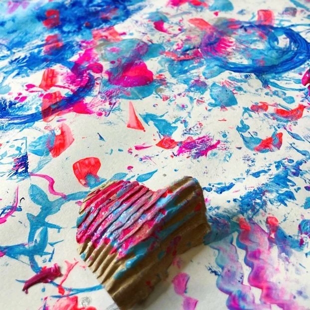 mixed media abstract artwork with paint marks of blue and pink covering paper.