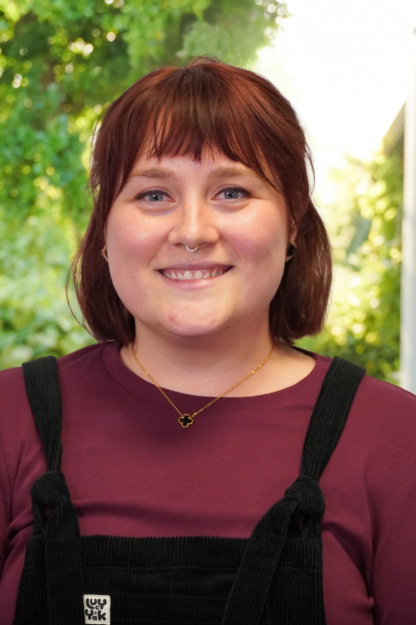 Autumn Robinson smiles while wearing black overalls and sporting red hair