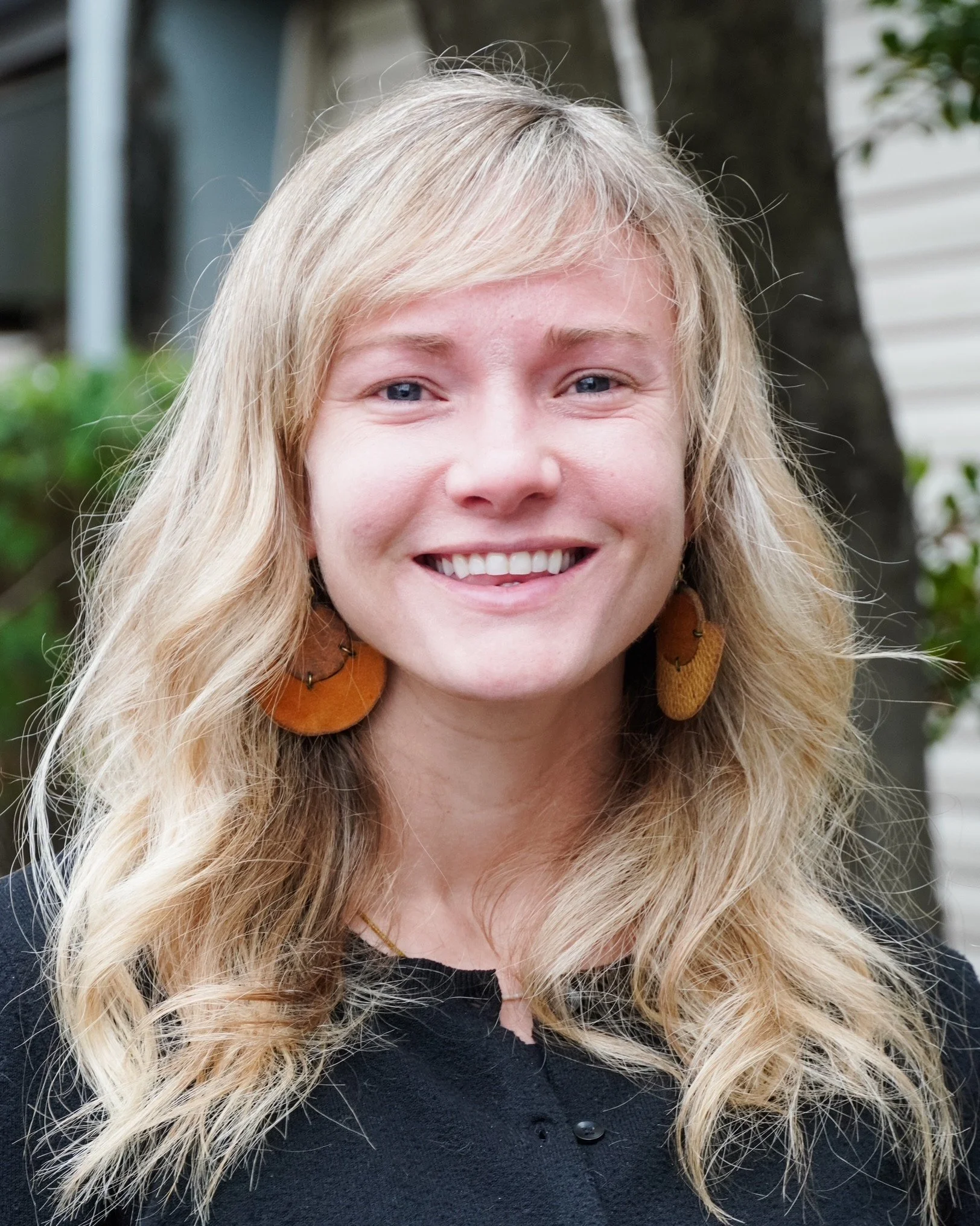 Lindsay Duncan stands smiling outside the BBBS office wearing earrings and a black button down