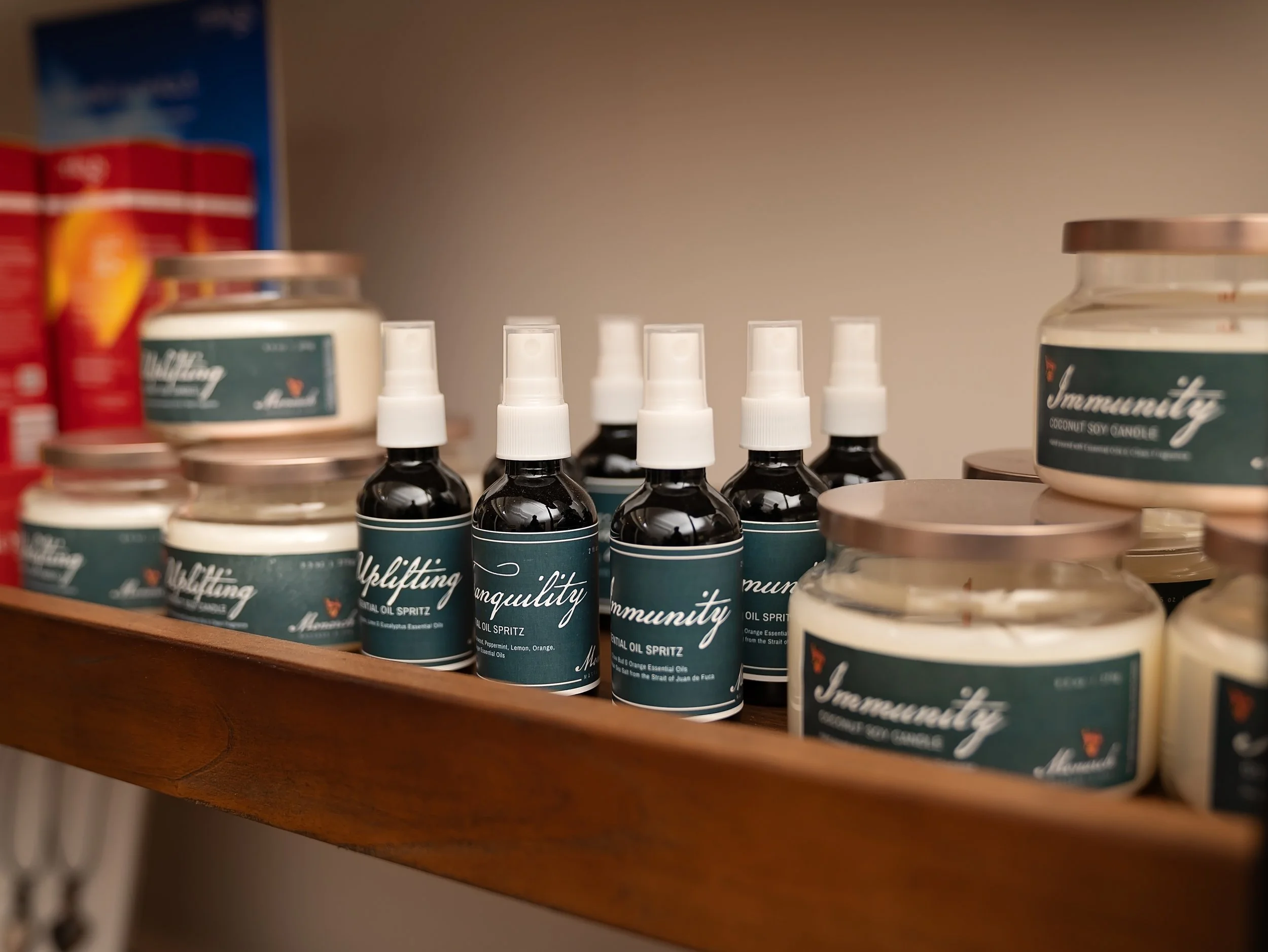 A shelf with small spray bottles labeled 'Mindfulness' and jars of candles, possibly scented, with the candle package in the background.