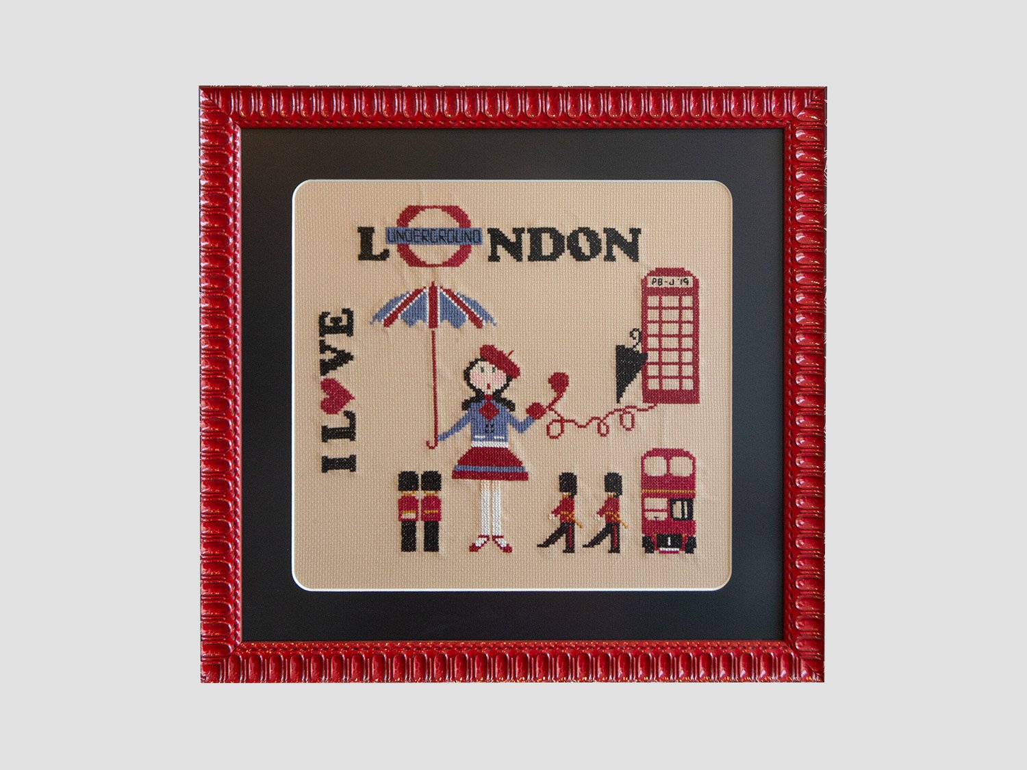 Counted cross stitch framed in red frame with rounded corners on mat.