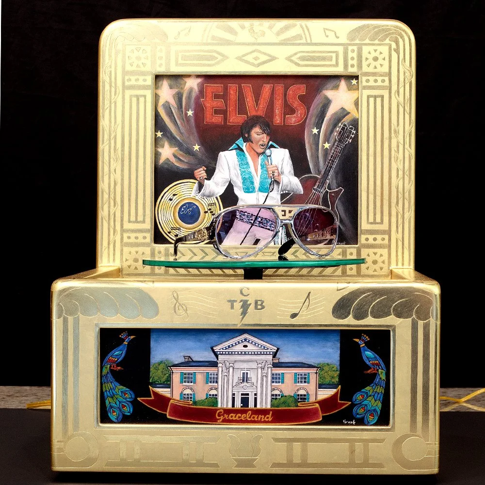 This 24ct gold-leafed turntable style display was designed to showcase a pair of Elvis Presley glasses. It features original artwork, a mirror rotating pedestal, and a motor that rotates the glasses.