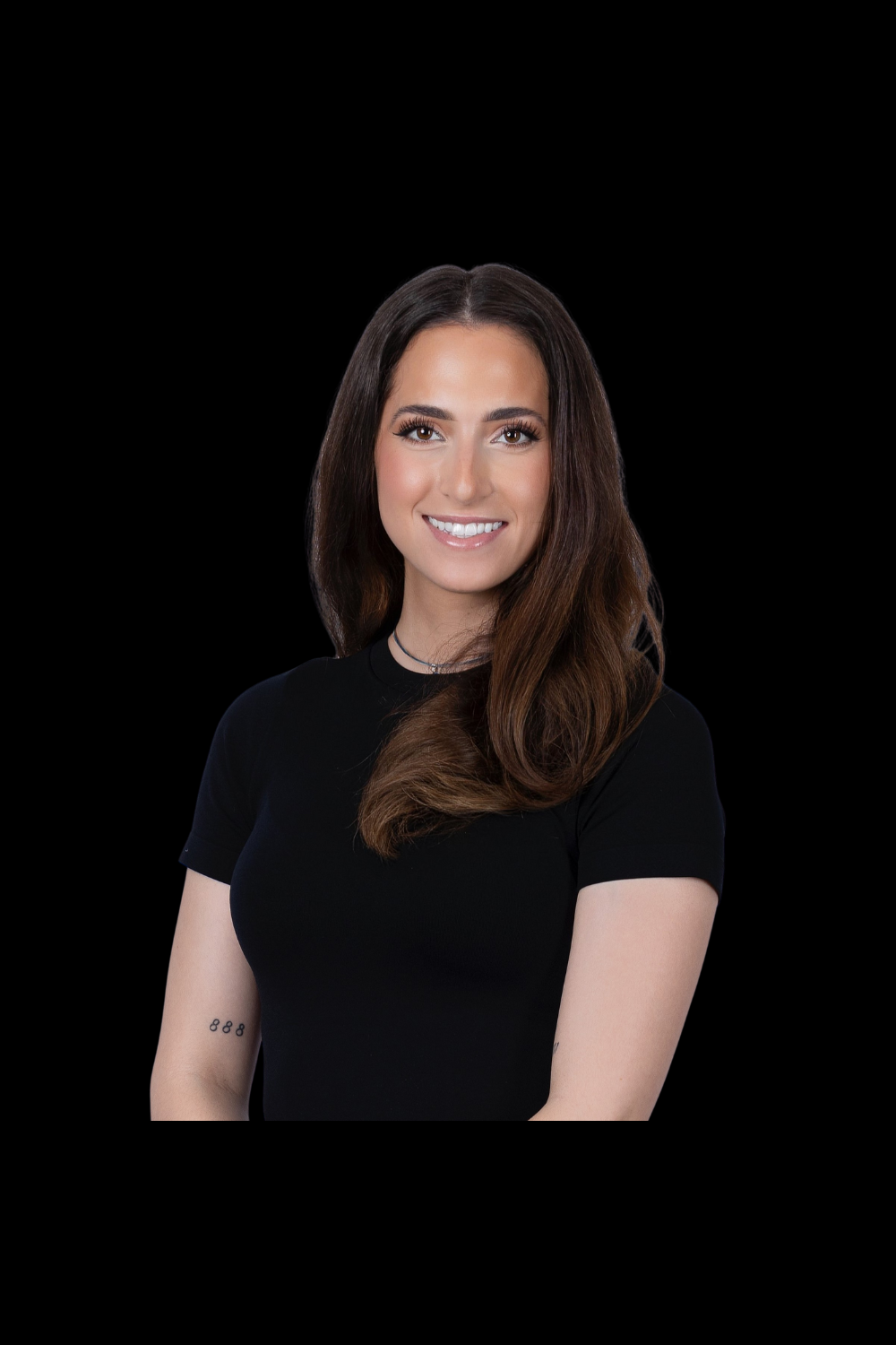 A young woman with long brown hair, smiling, wearing a black shirt and a necklace, posed against a black background.