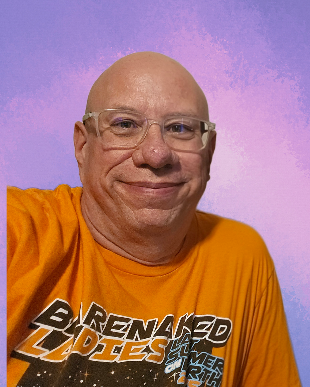 A middle-aged man with glasses wearing an orange T-shirt with space-themed text, smiling at the camera against a purple gradient background.