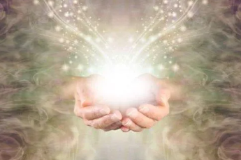 Hands holding a glowing light surrounded by sparkles.