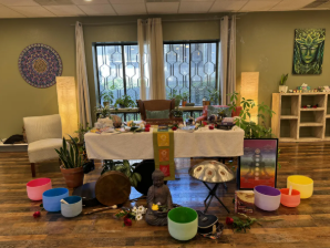 Sound therapy space prepared with colorful singing bowls, candles, plants and decorations.