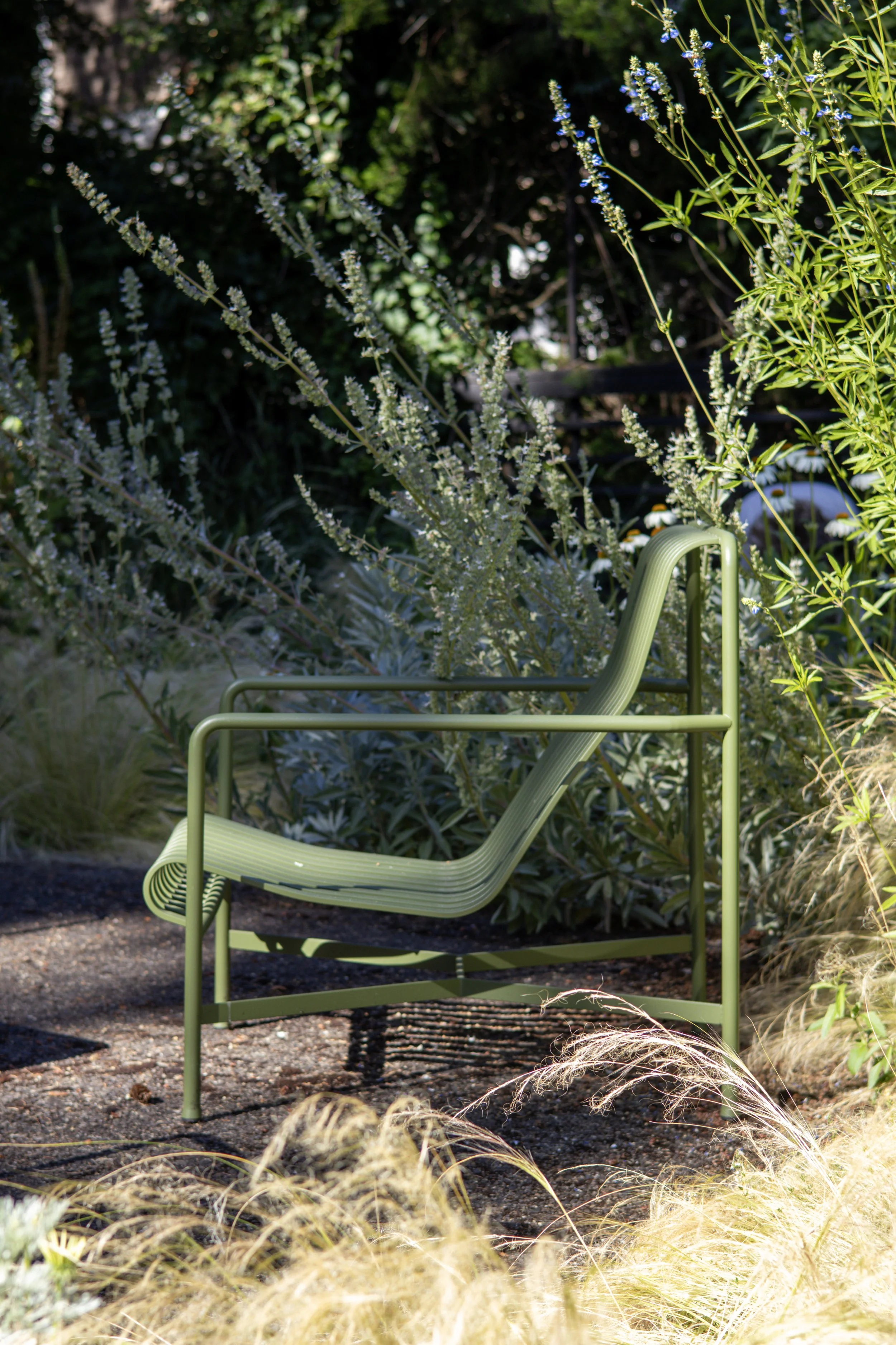 a green modern chair on a front yard patio next to wild native plants and a landscape