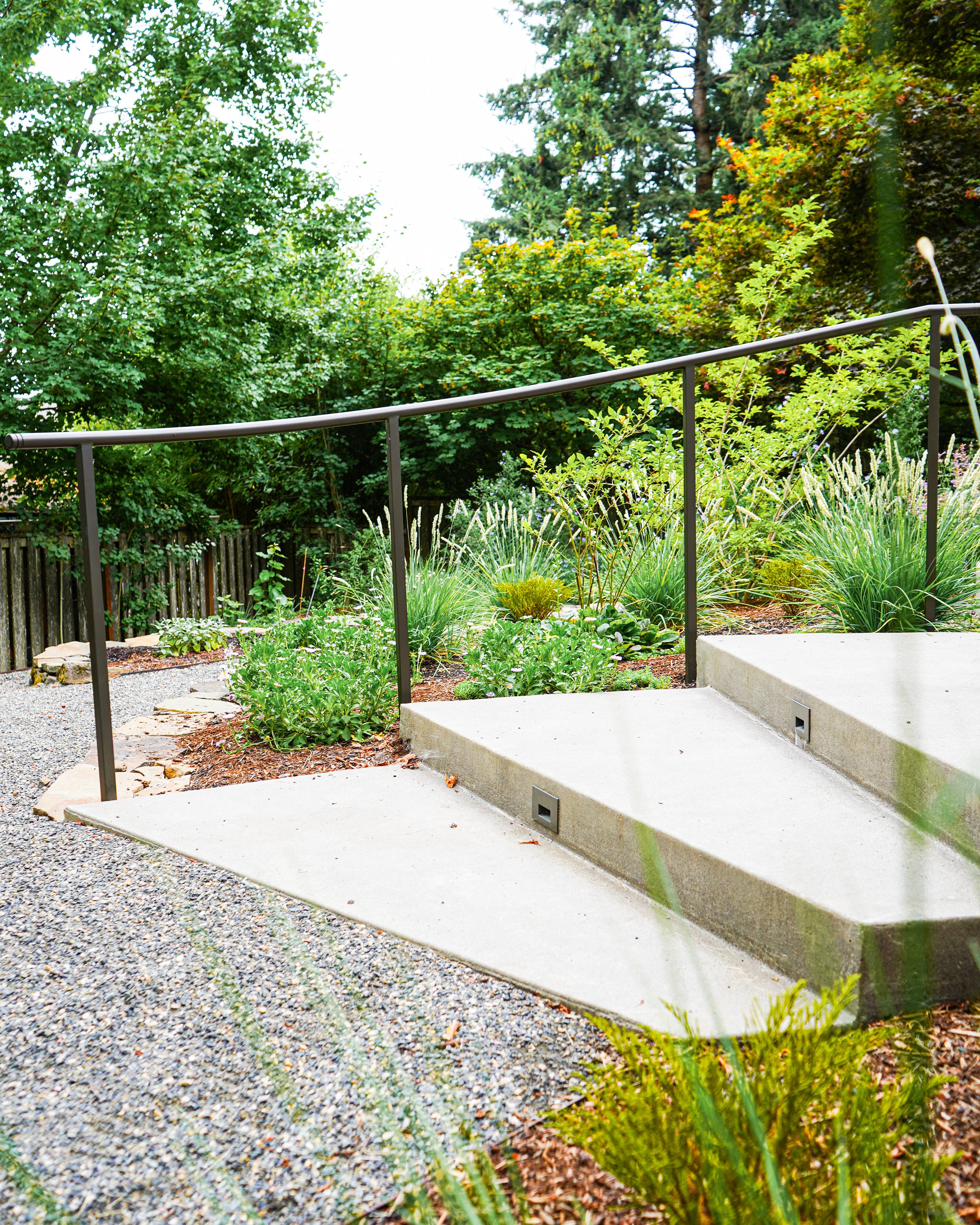Stairs fit with a hand rail and built in lighting on a sloped property in the Pacific Northwest