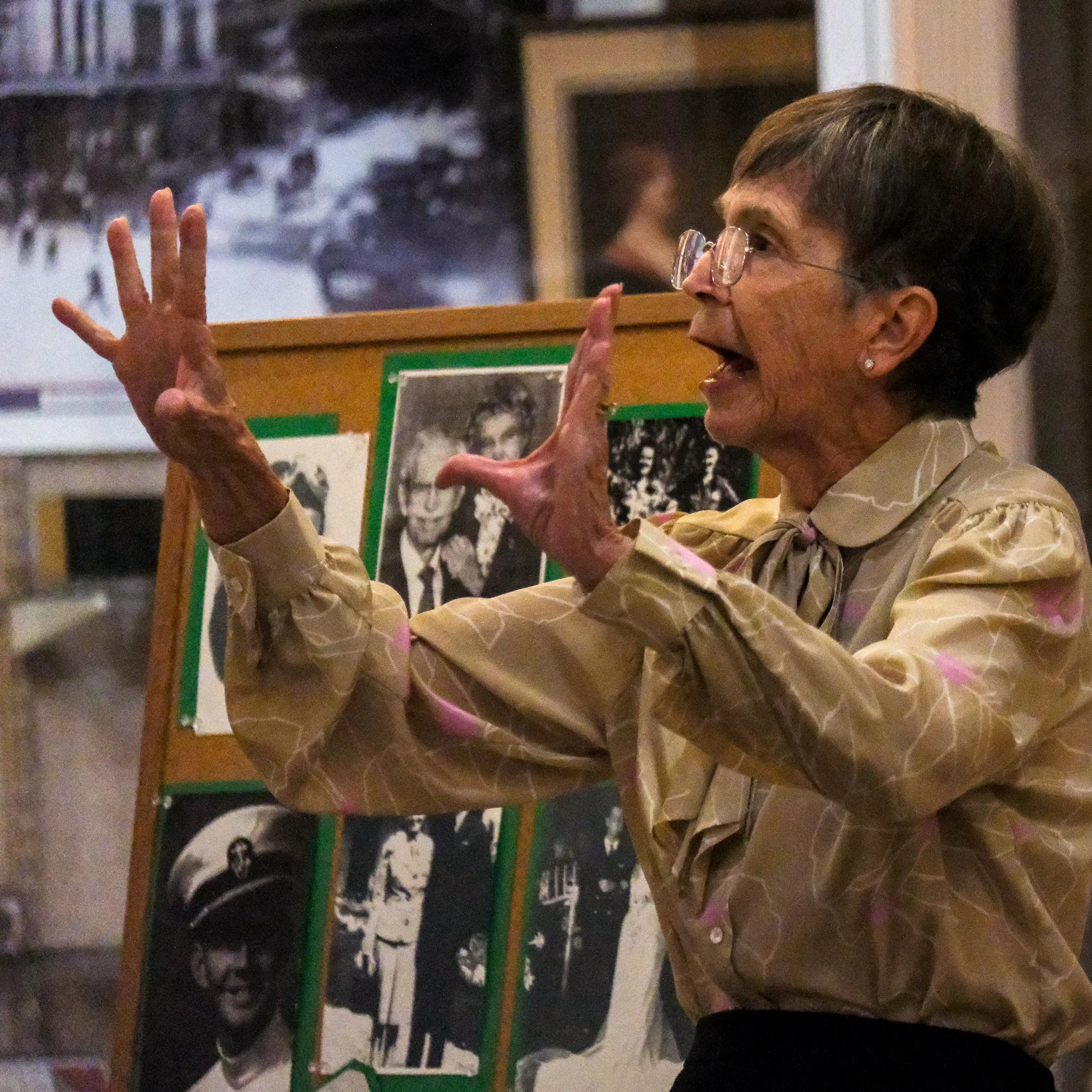 Caryn Long with raised hands, telling the story of DeLand's first female letter carrier at the Conrad Center.