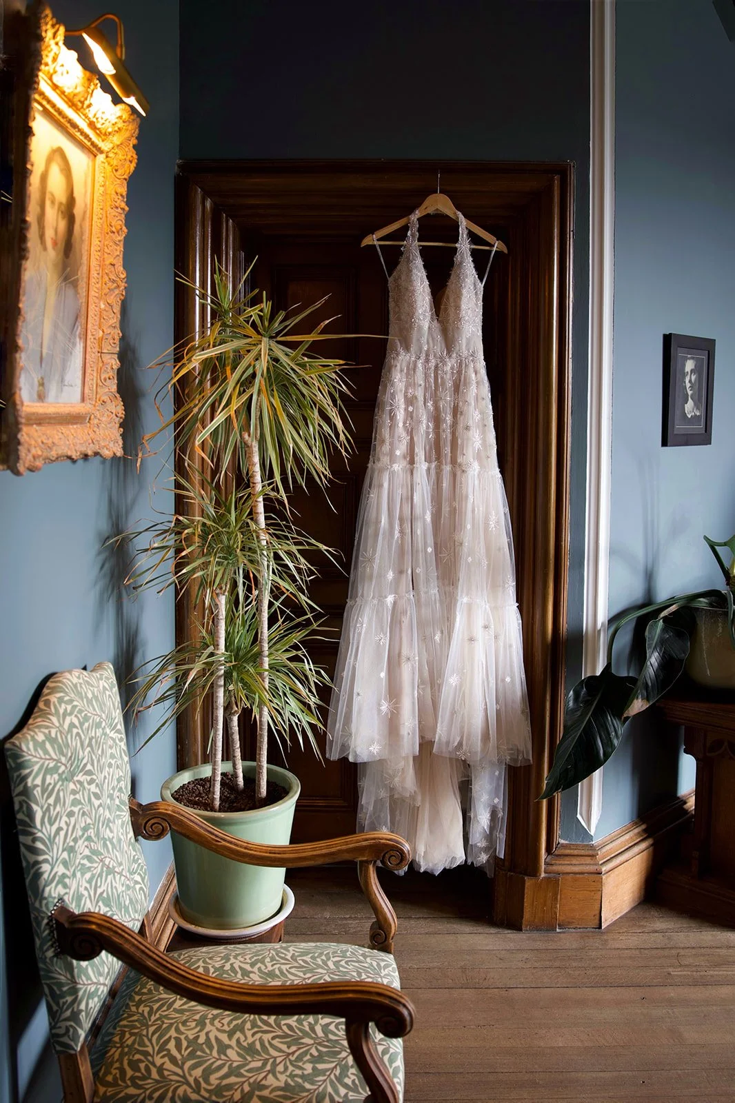 A bride in a white wedding gown holding a bouquet of flowers stands in a vintage library with wooden bookshelves and a piano.