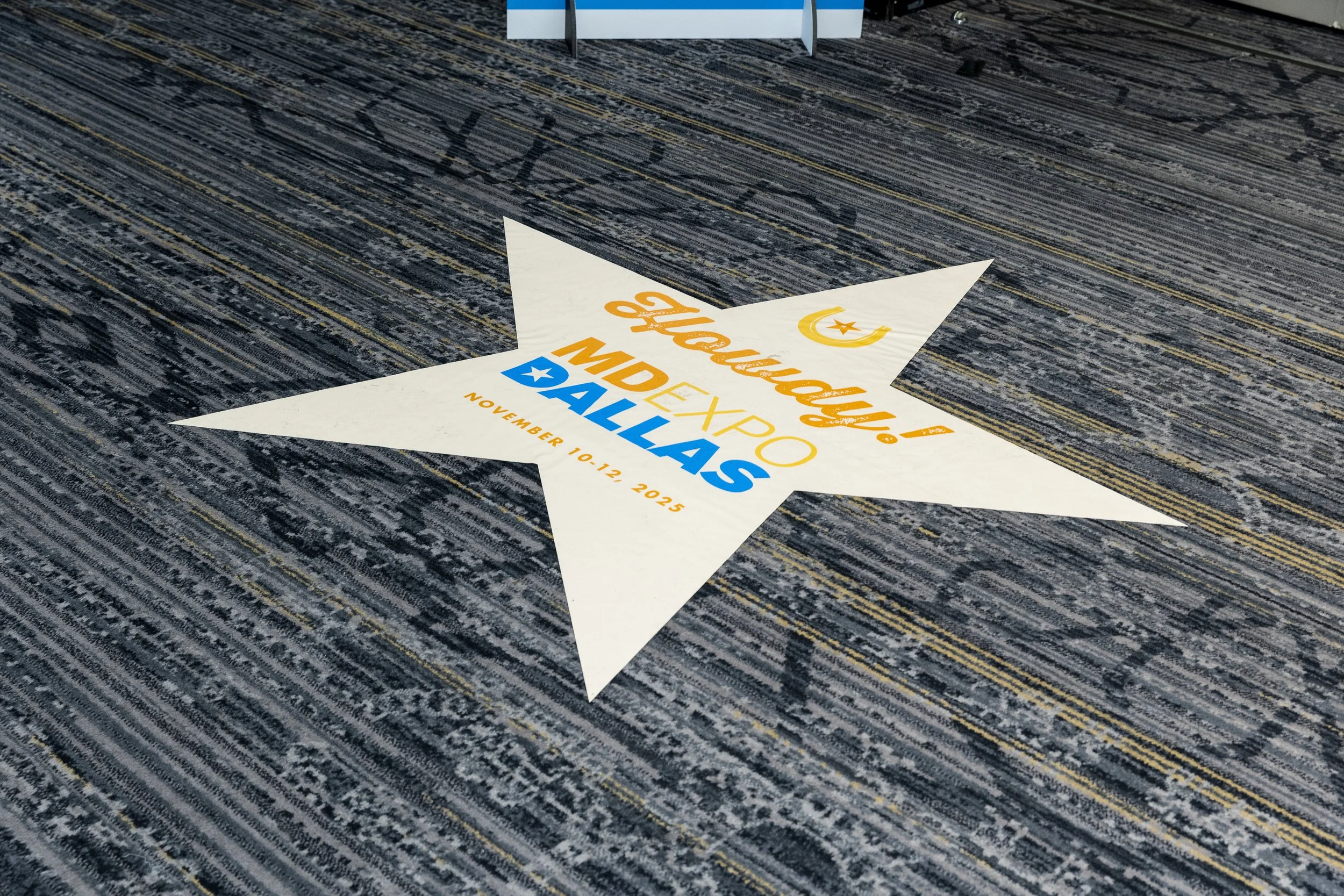 Floor decal in the shape of a star with promotional text for the Houston International Auto Show, scheduled for November 10-12, 2025.