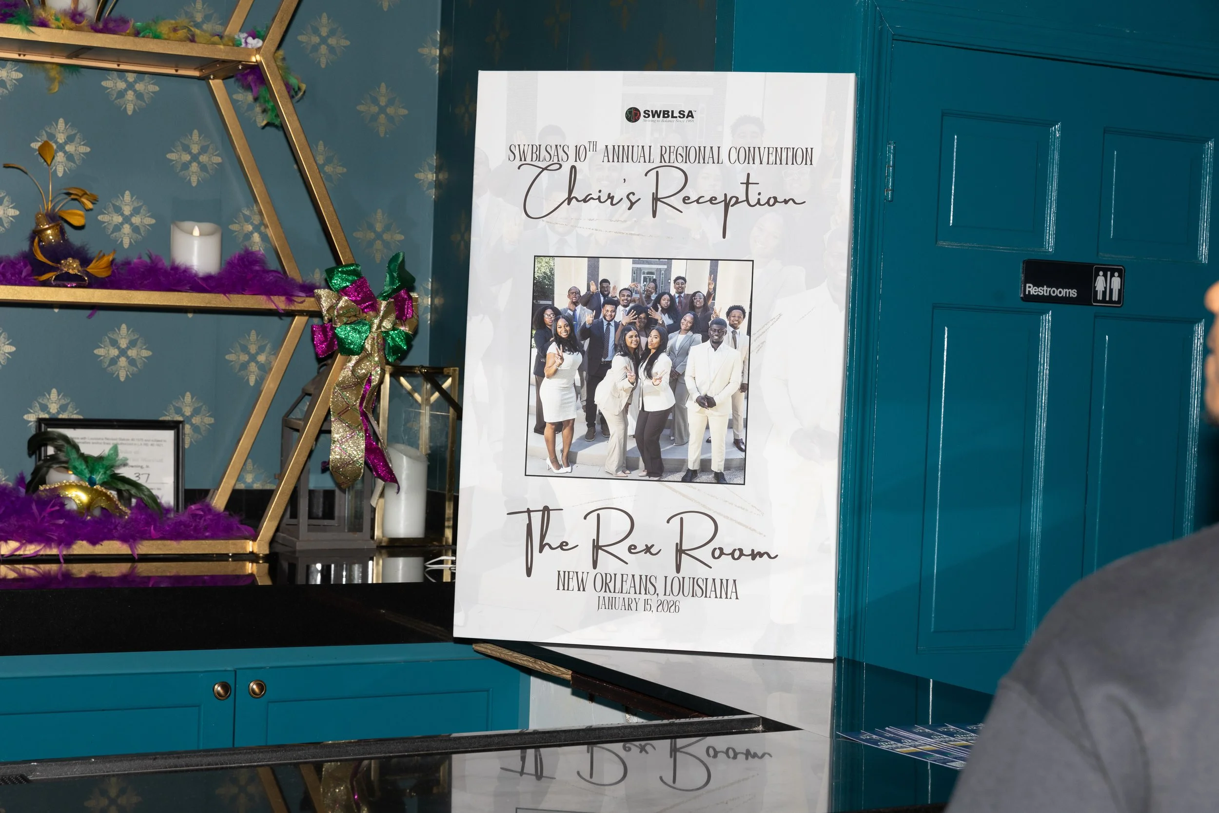 Event sign for SWBLSA's 10th annual regional convention, chairs reception, featuring a group photo of diverse attendees, held at The Rex Room in New Orleans, Louisiana on January 15, 2026.