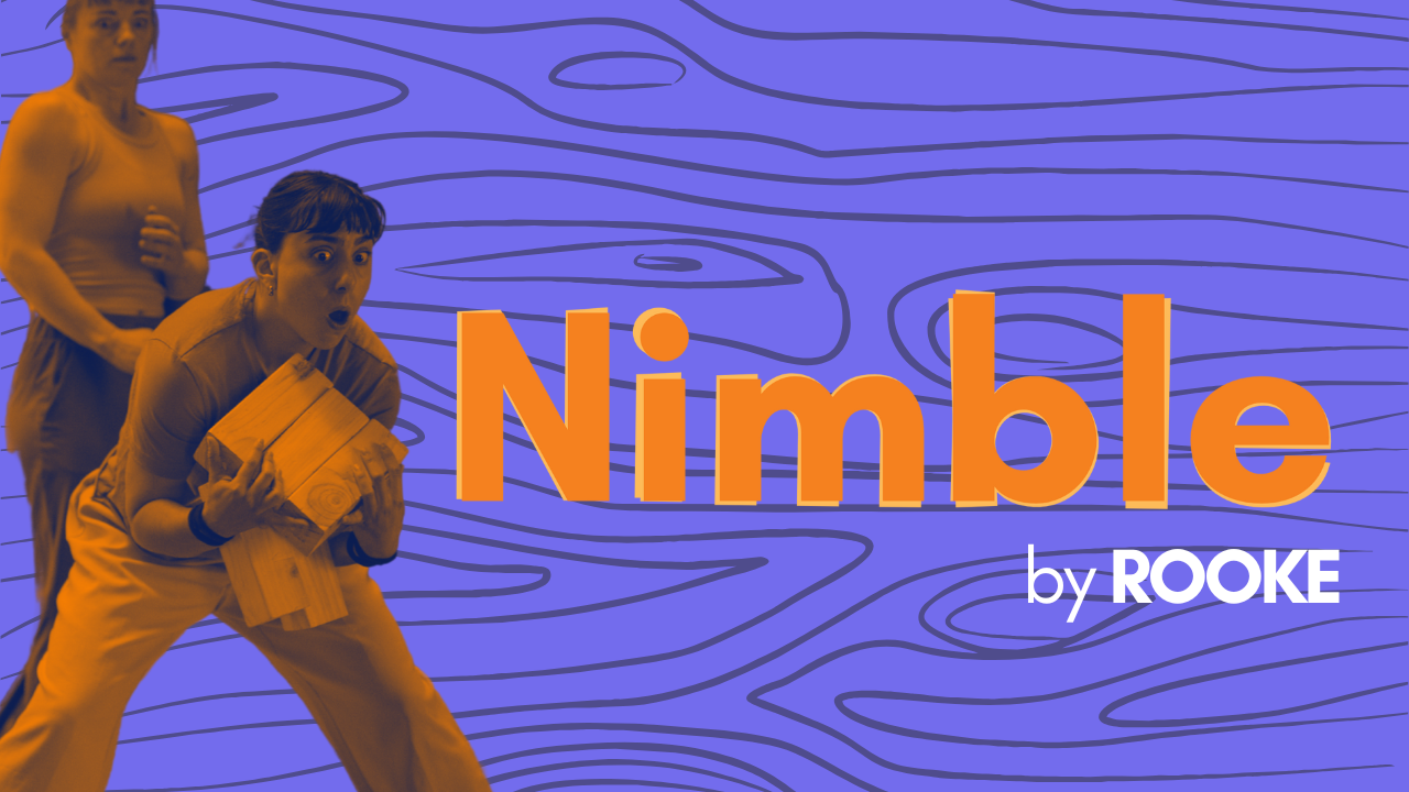 Two girls look shocked, they've accidentally knocked over a stack of blocks. they are in black and orange and the background is purple woodgrain