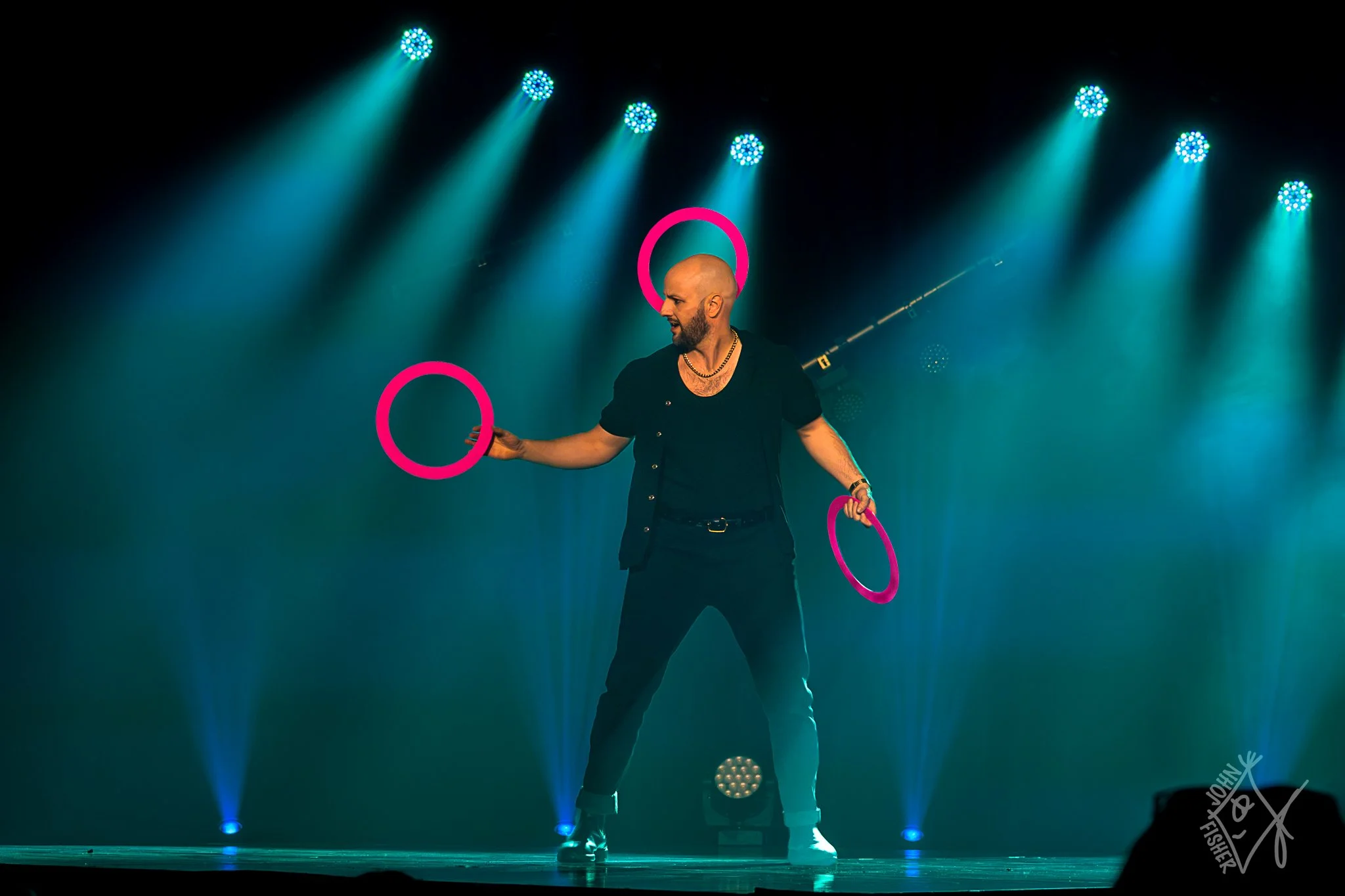 A man is juggling three pink rings