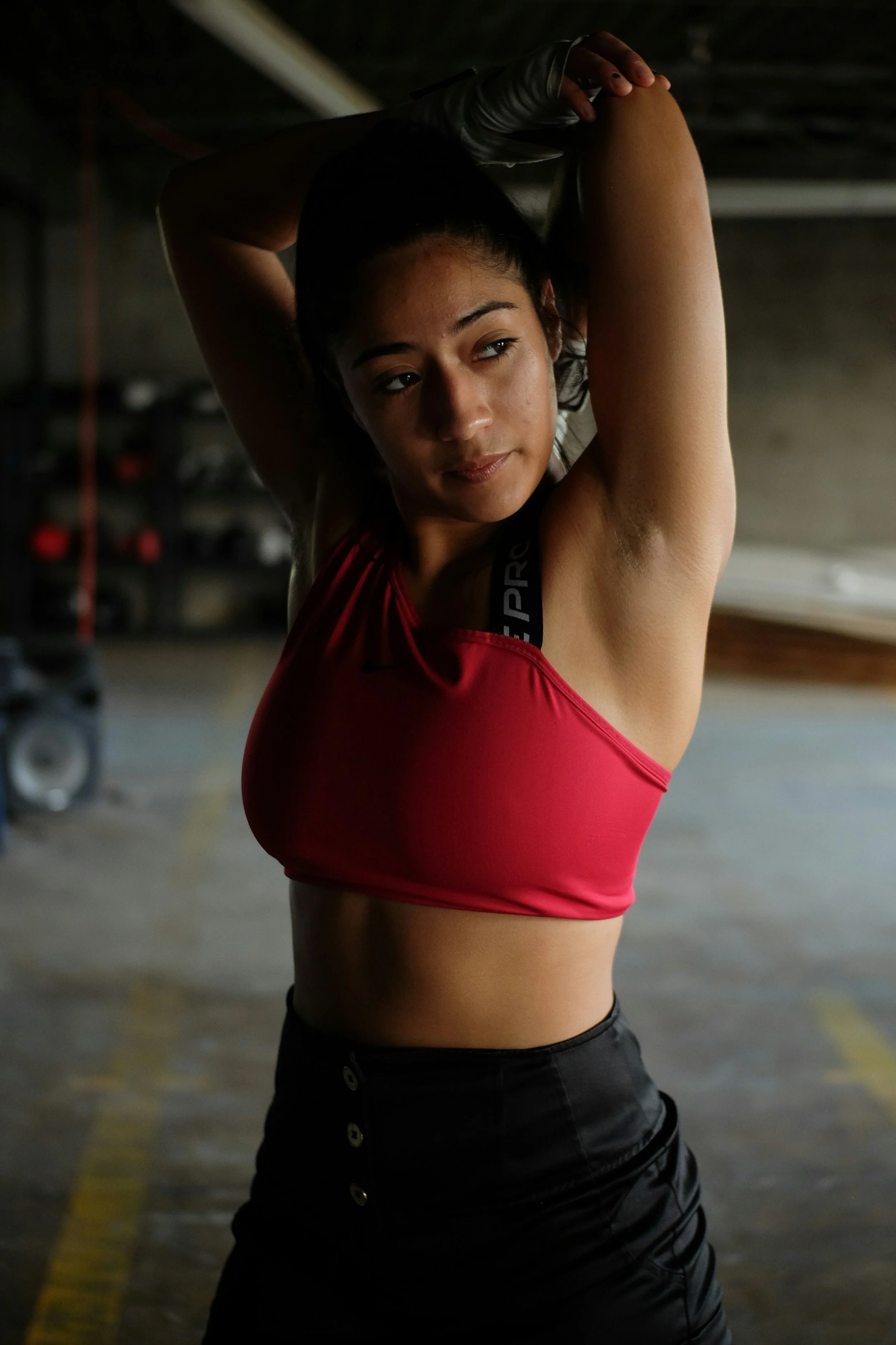 Young woman in workout clothes stretching in a parking garage.