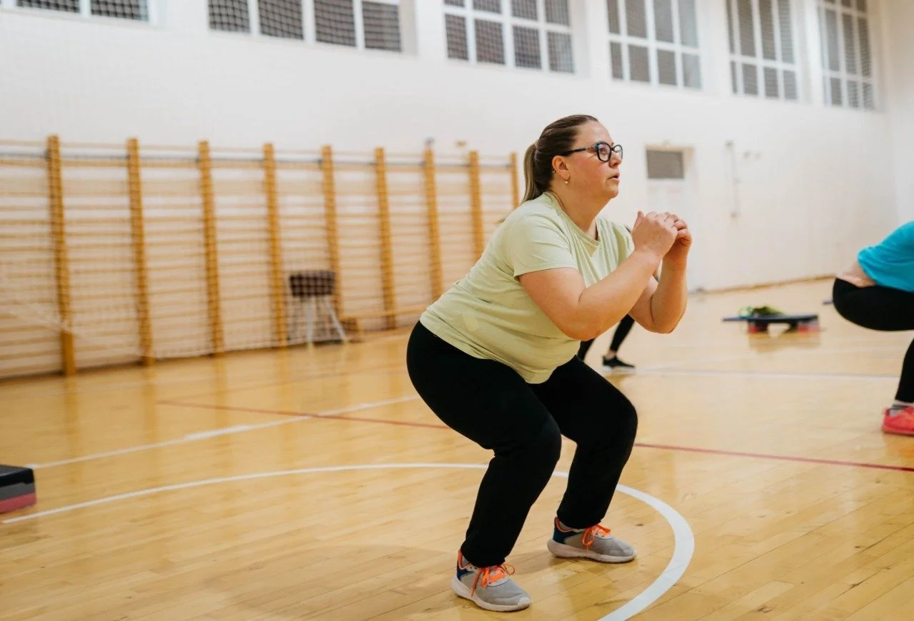 Woman performing a squat exercise in a gymnasium.