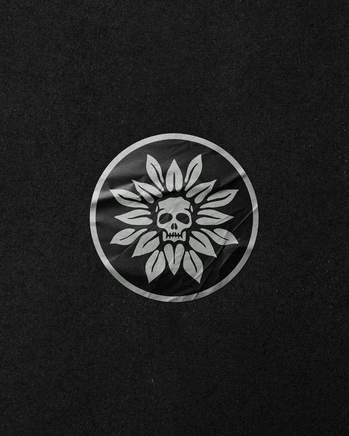 White circular logo with a skull in the center, surrounded by leaf shapes on a black background.
