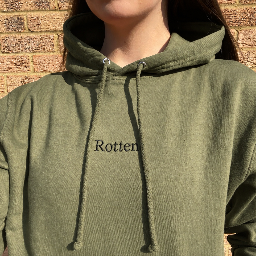 Khaki Rotten Hoodie with black embroidered lettering worn outdoors