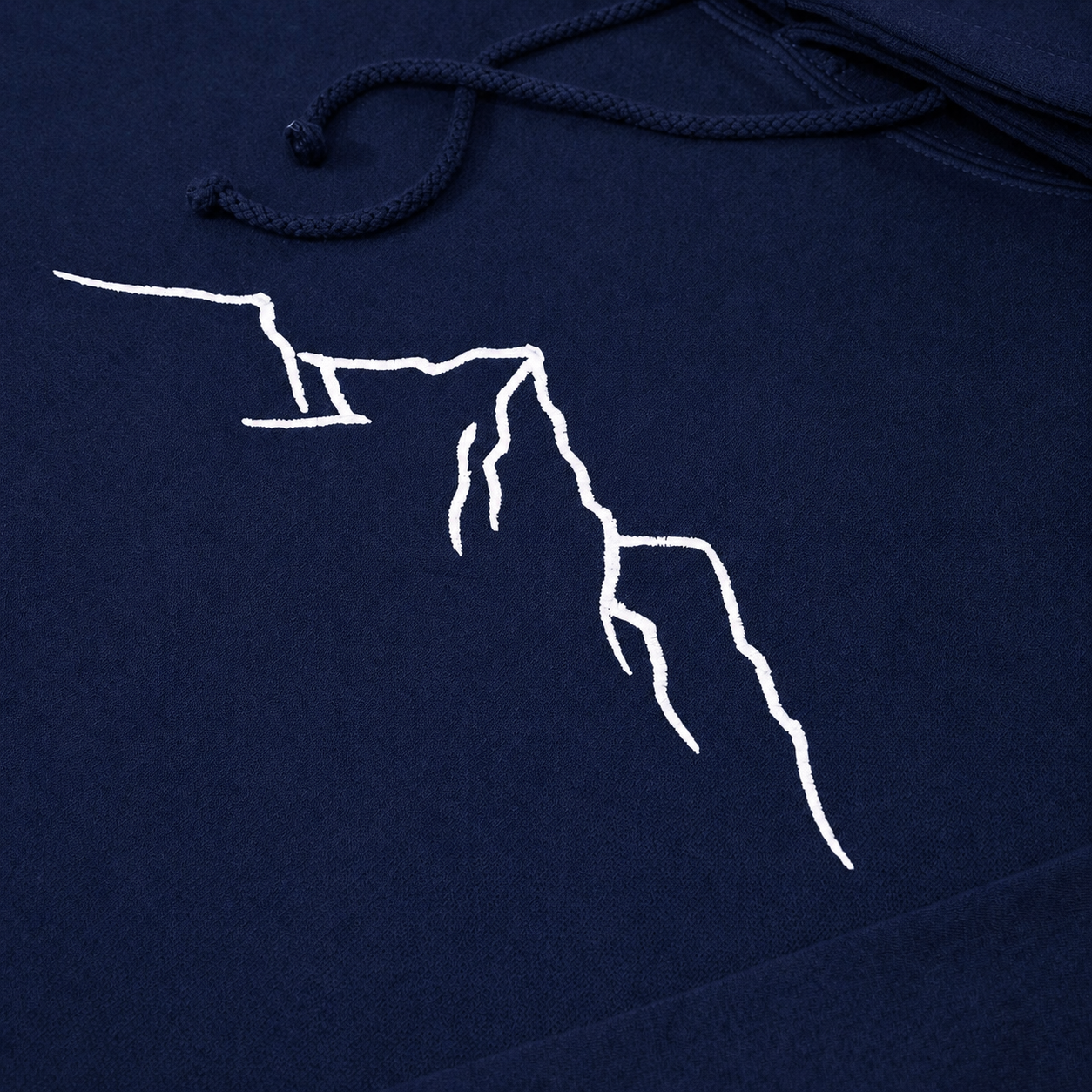 Close-up of white mountain outline embroidery on a navy hoodie