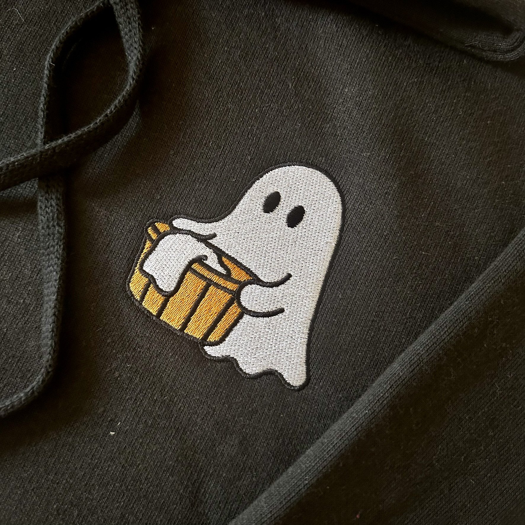 Close-up of cute ghost and laundry basket embroidery on a black hoodie