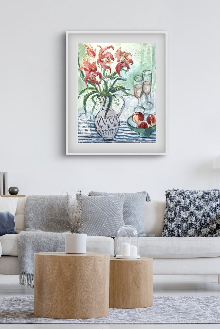 A pretty still life floral painting in pinks, blues and greens, hanging on a wall above a sofa