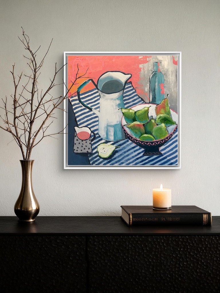a still life painting hanging on the wall above a dresser. The painting is in pink and blue and shows an old enamel jug and a dish of pears