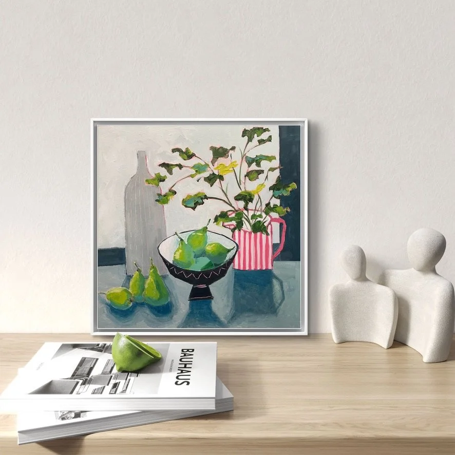 A delightful, colourful painting of a still life shown on the wall above a tabletop with books and simple sculpture