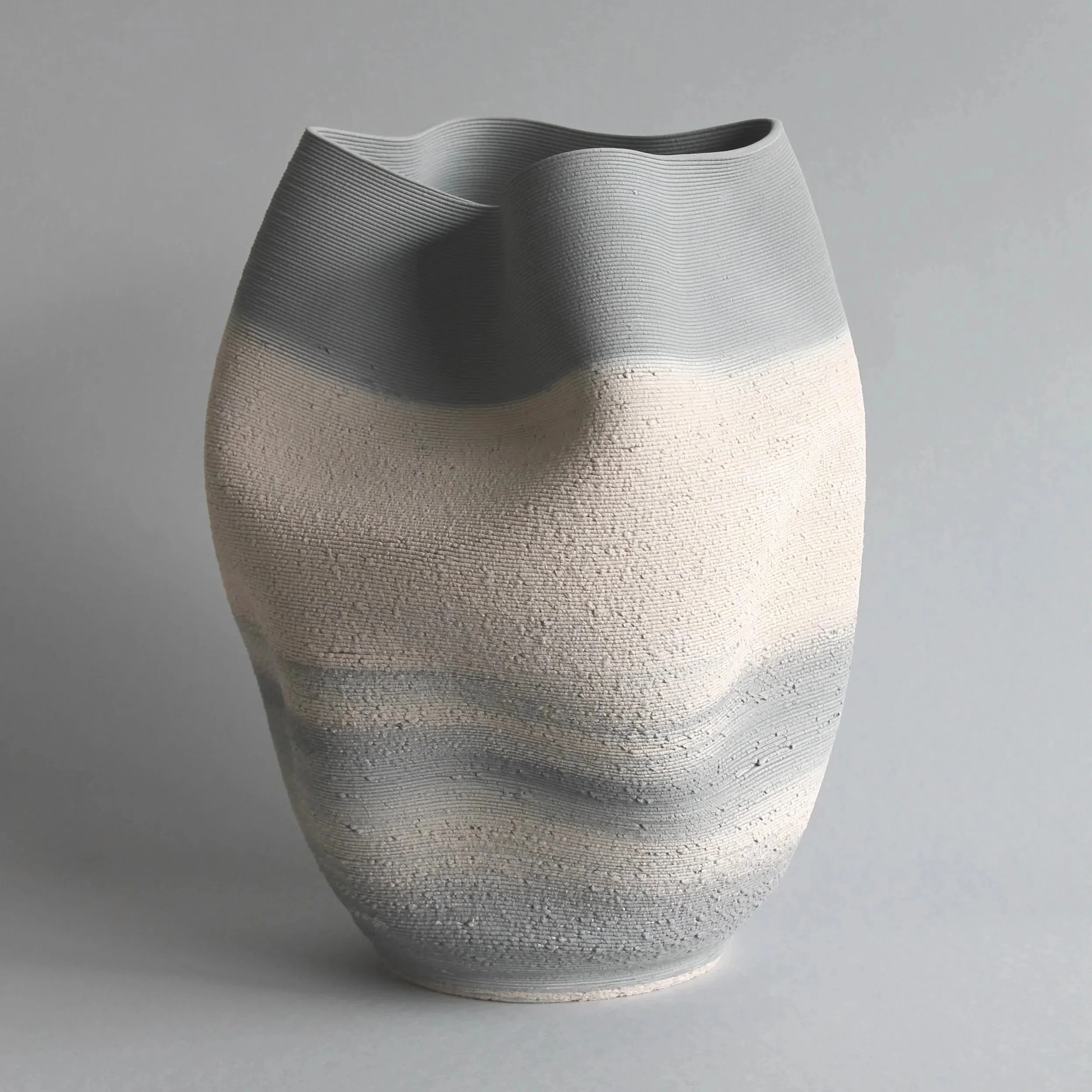 grey and white layered ceramic pot on grey background.