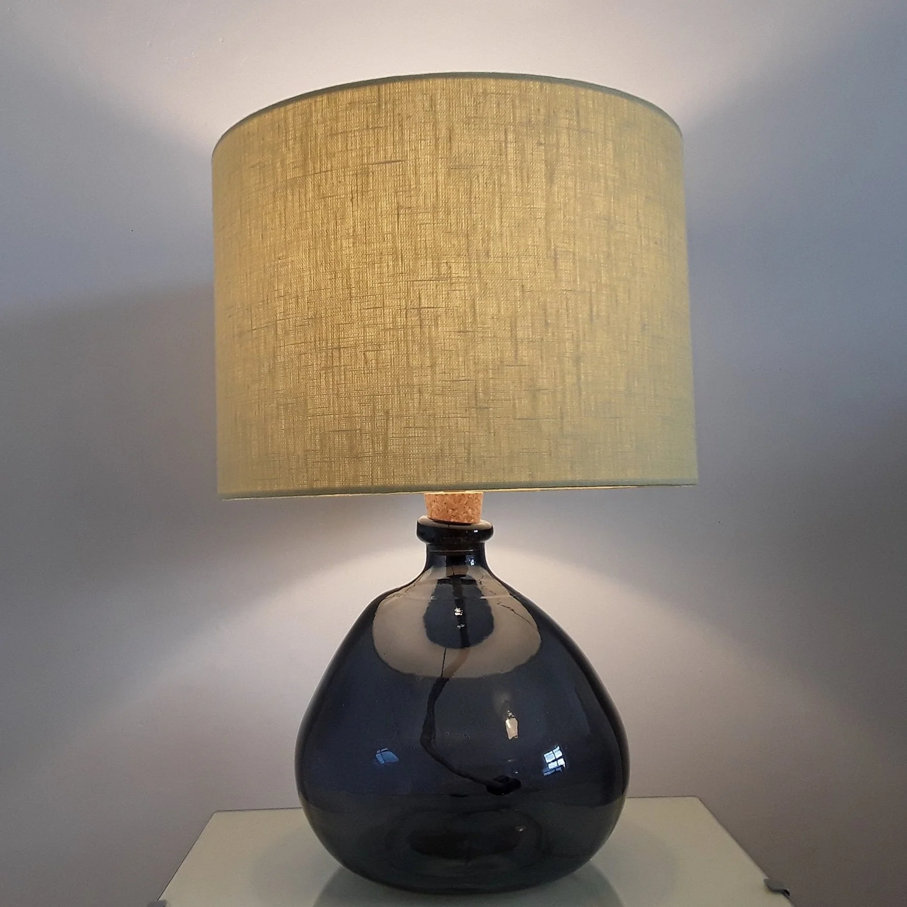 Citrus yellow ,drum shaped shade on glass lamp. The shade is illuminated and giving a soft yelllowglow.