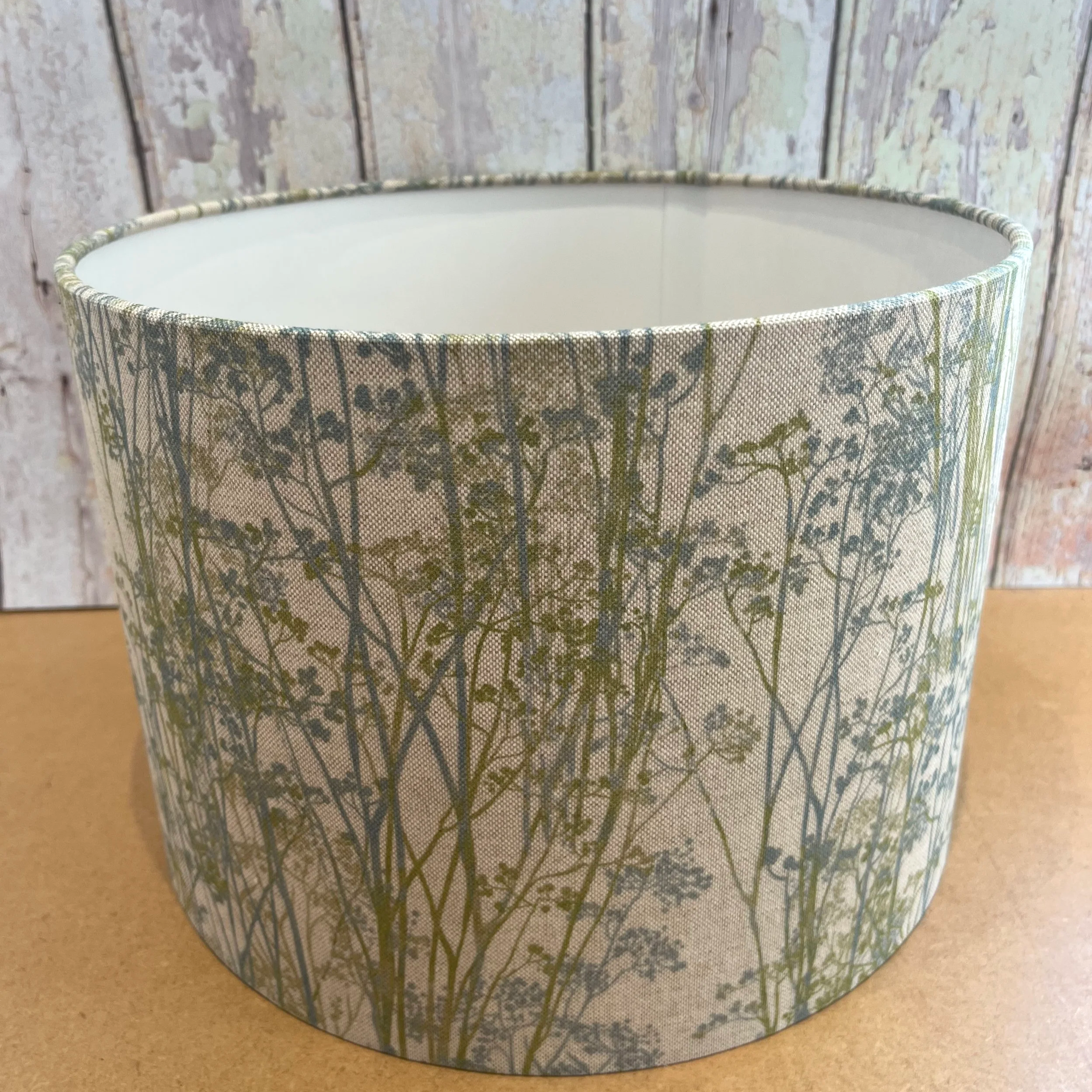 Hedgerow print lampshade in blue green and natural colour with a white lining.