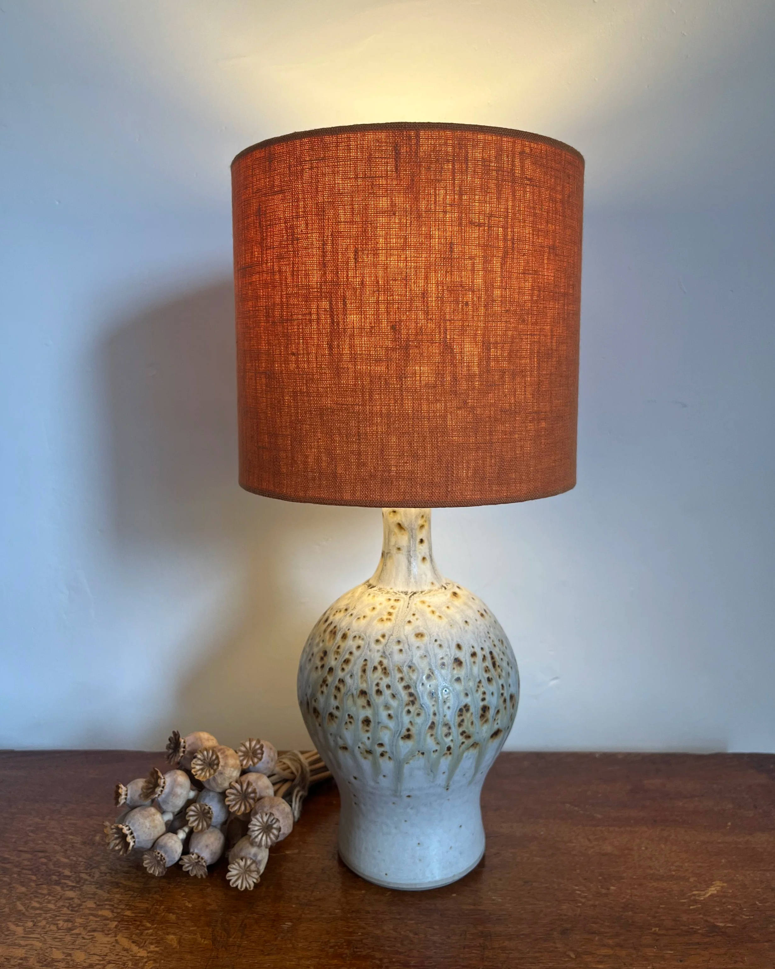 Orange linen lampshade, illuminated on ceramic lamp