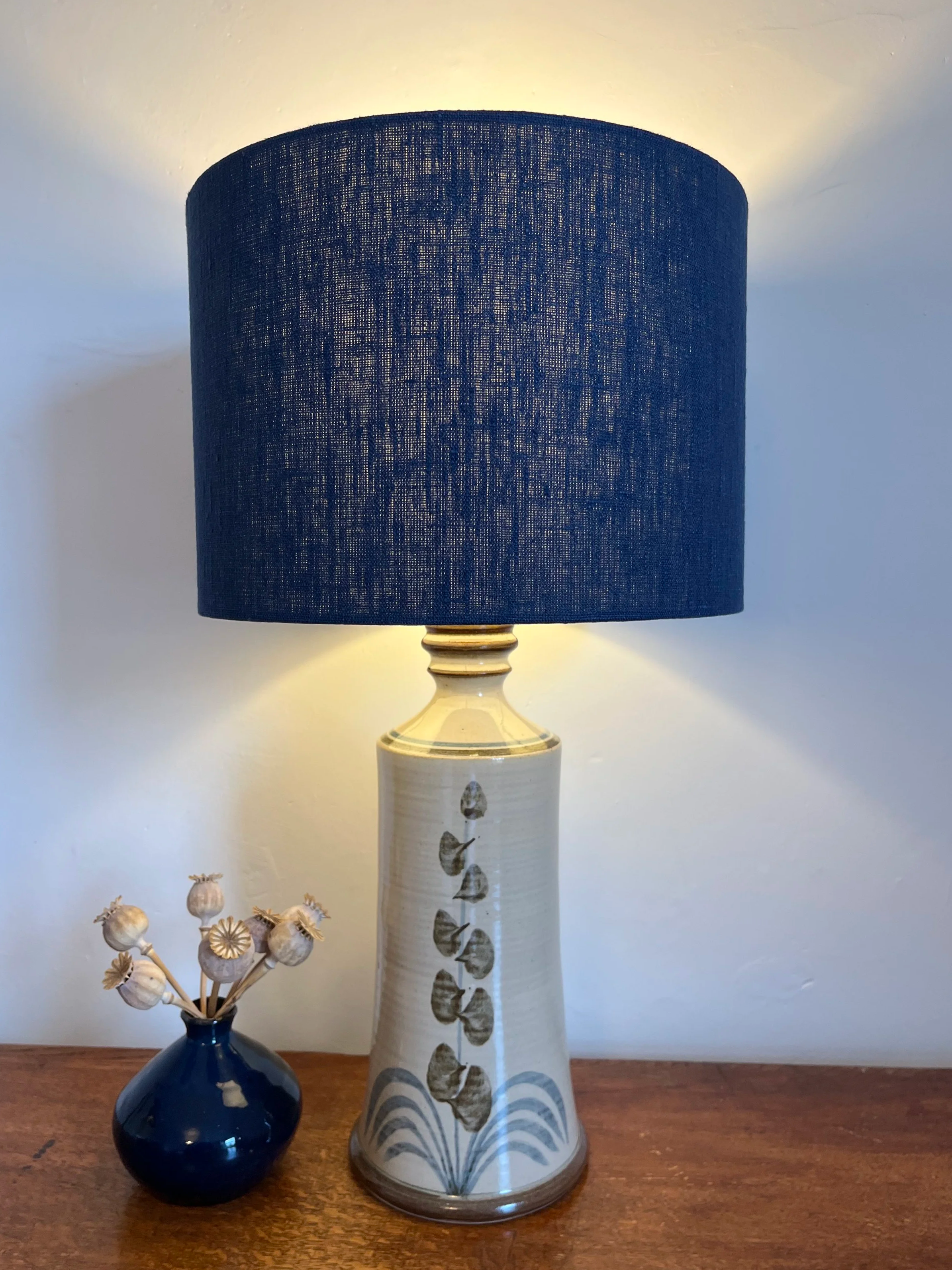 Navy linen lampshade, illuminated giving a warm glow.