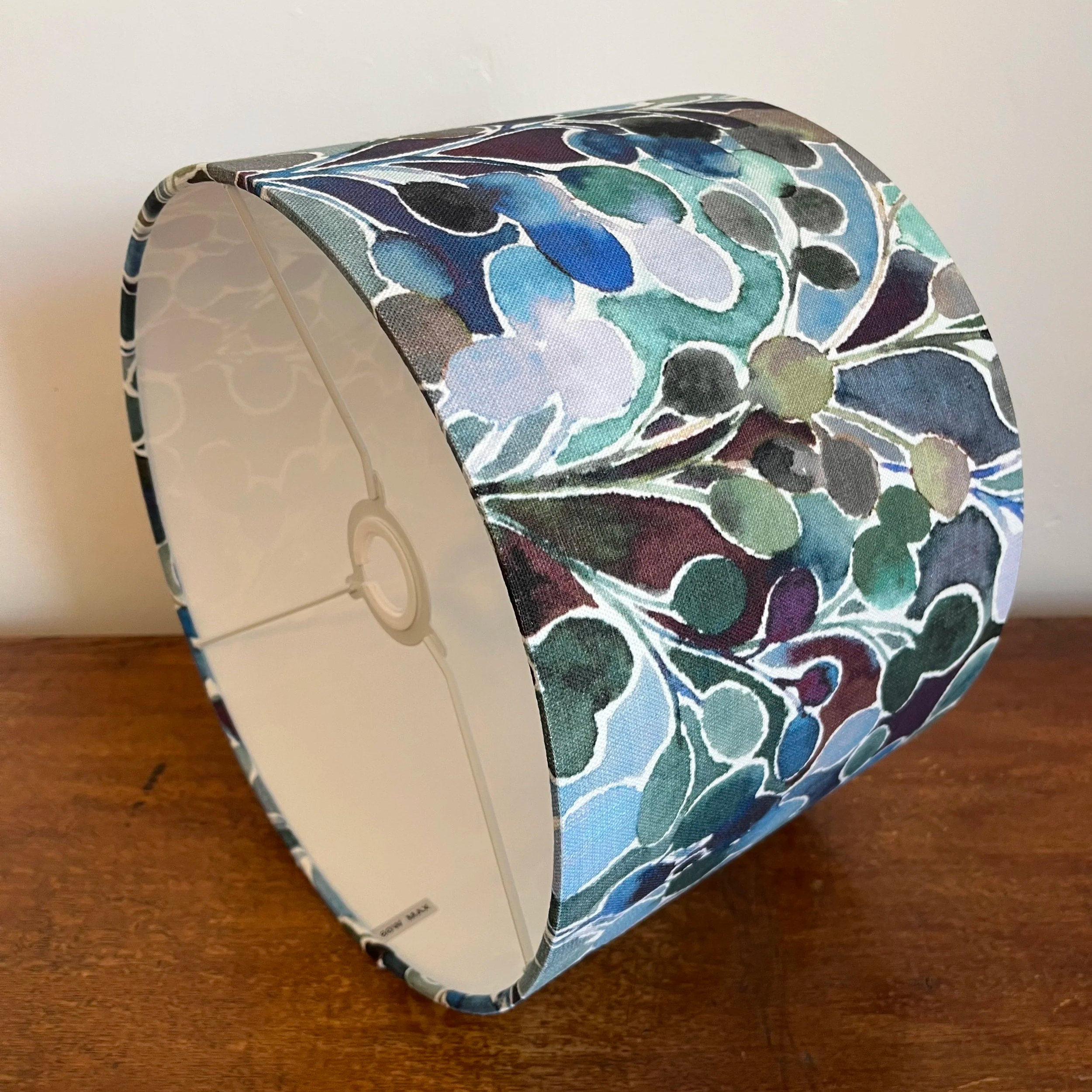 Drum lampshade with leafy green, blue design with white lining.